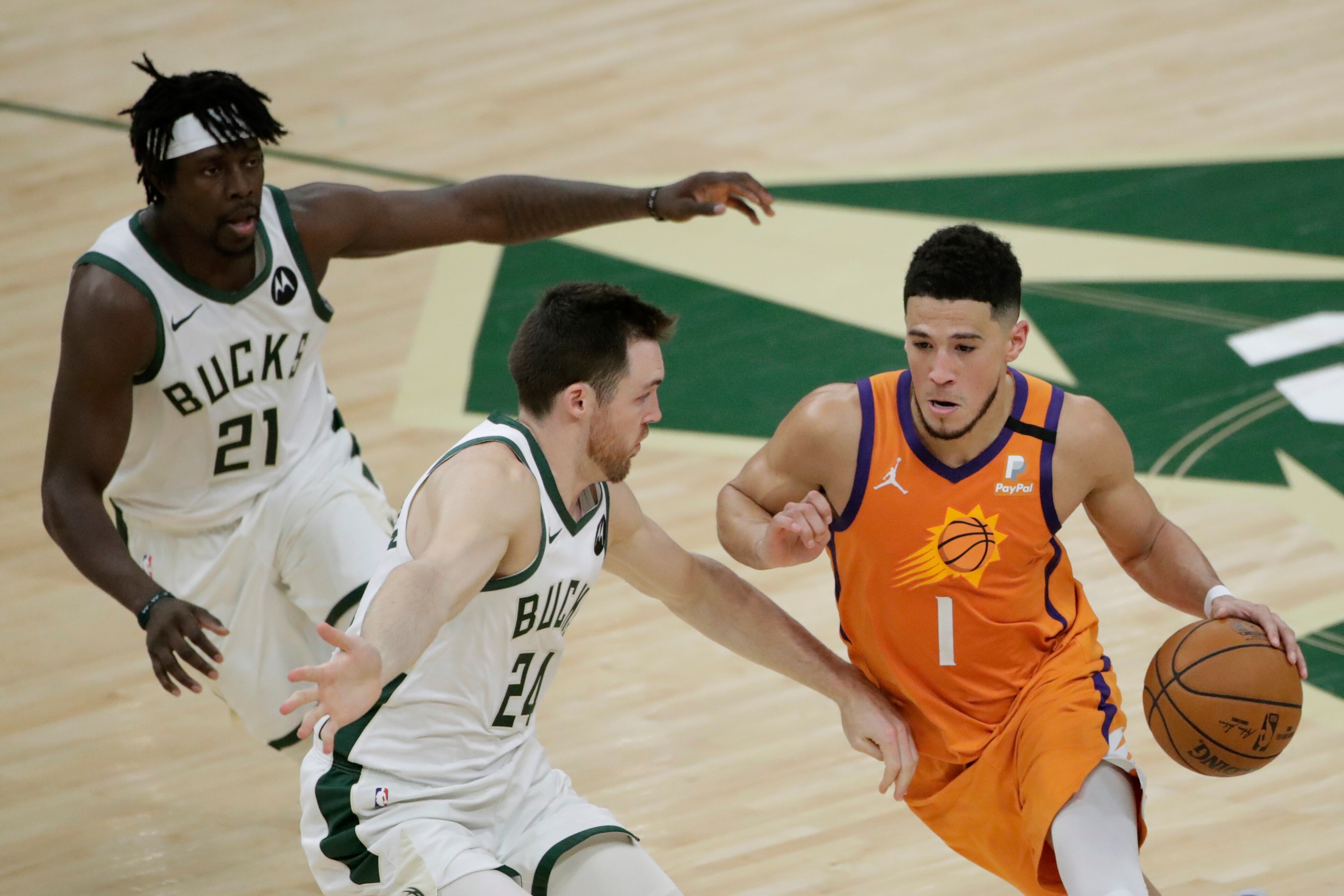 Phoenix Suns guard Devin Booker (1) drives past Milwaukee Bucks guard Pat Connaughton (24) and guard Jrue Holiday (21) during the first half of Game 4 of basketball's NBA Finals Wednesday, July 14, 2021, in Milwaukee. (AP Photo/Aaron Gash)