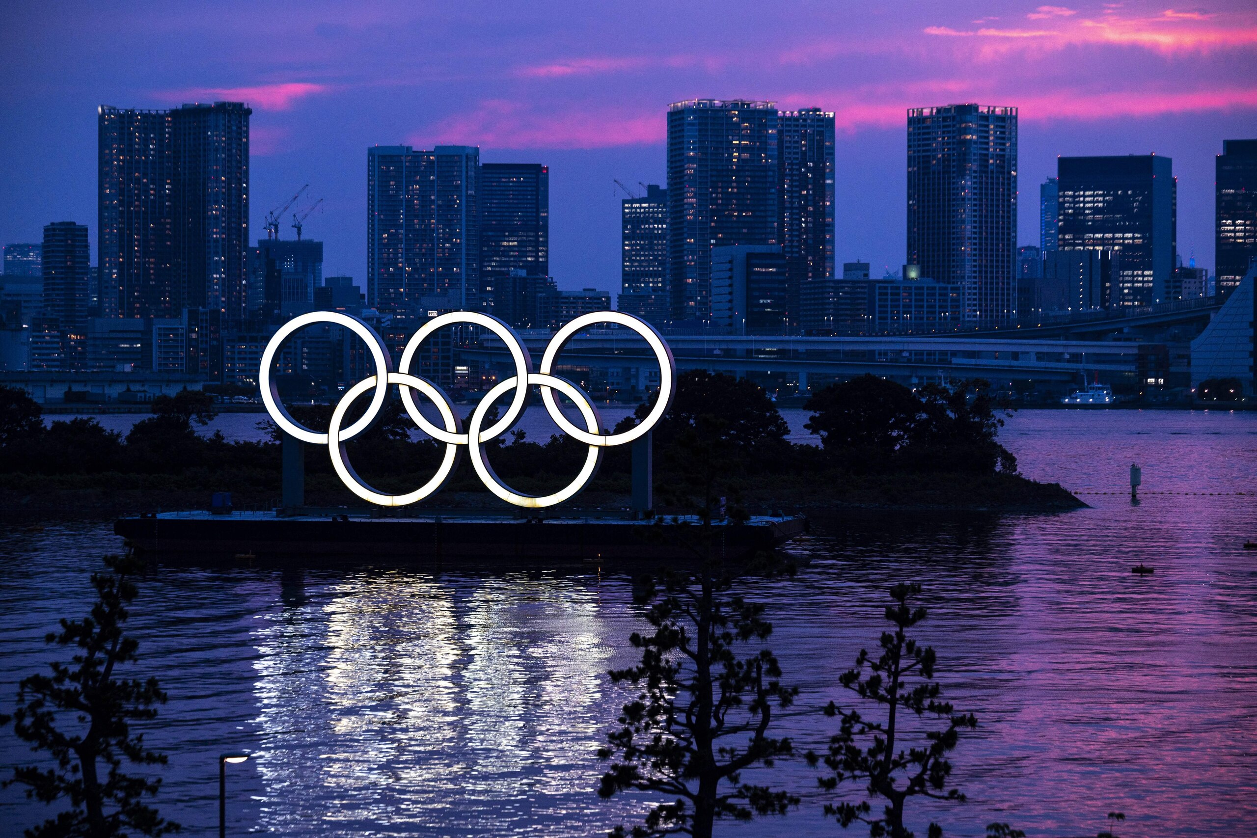 A general view shows the Olympic rings lit up at dusk on the Odaiba waterfront in Tokyo on Juky 12, 2021. (Photo by Charly TRIBALLEAU / AFP) (Photo by CHARLY TRIBALLEAU/AFP via Getty Images)