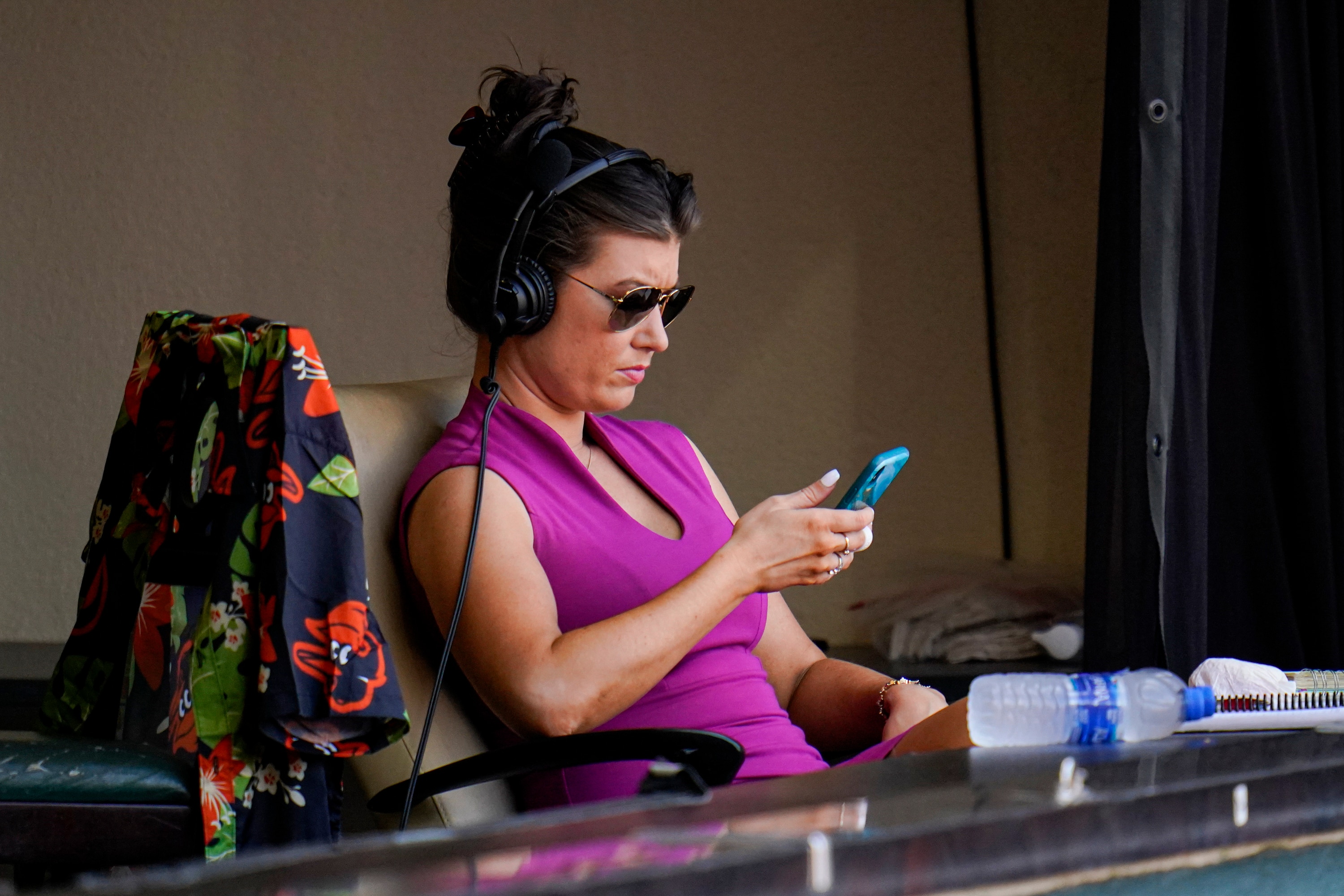 Melanie Newman, play-by-play broadcaster for the Baltimore Orioles, looks at her phone between innings during the fourth inning of a baseball game between the Baltimore Orioles and the Chicago White Sox, Saturday, July 10, 2021, in Baltimore. (AP Photo/Julio Cortez)