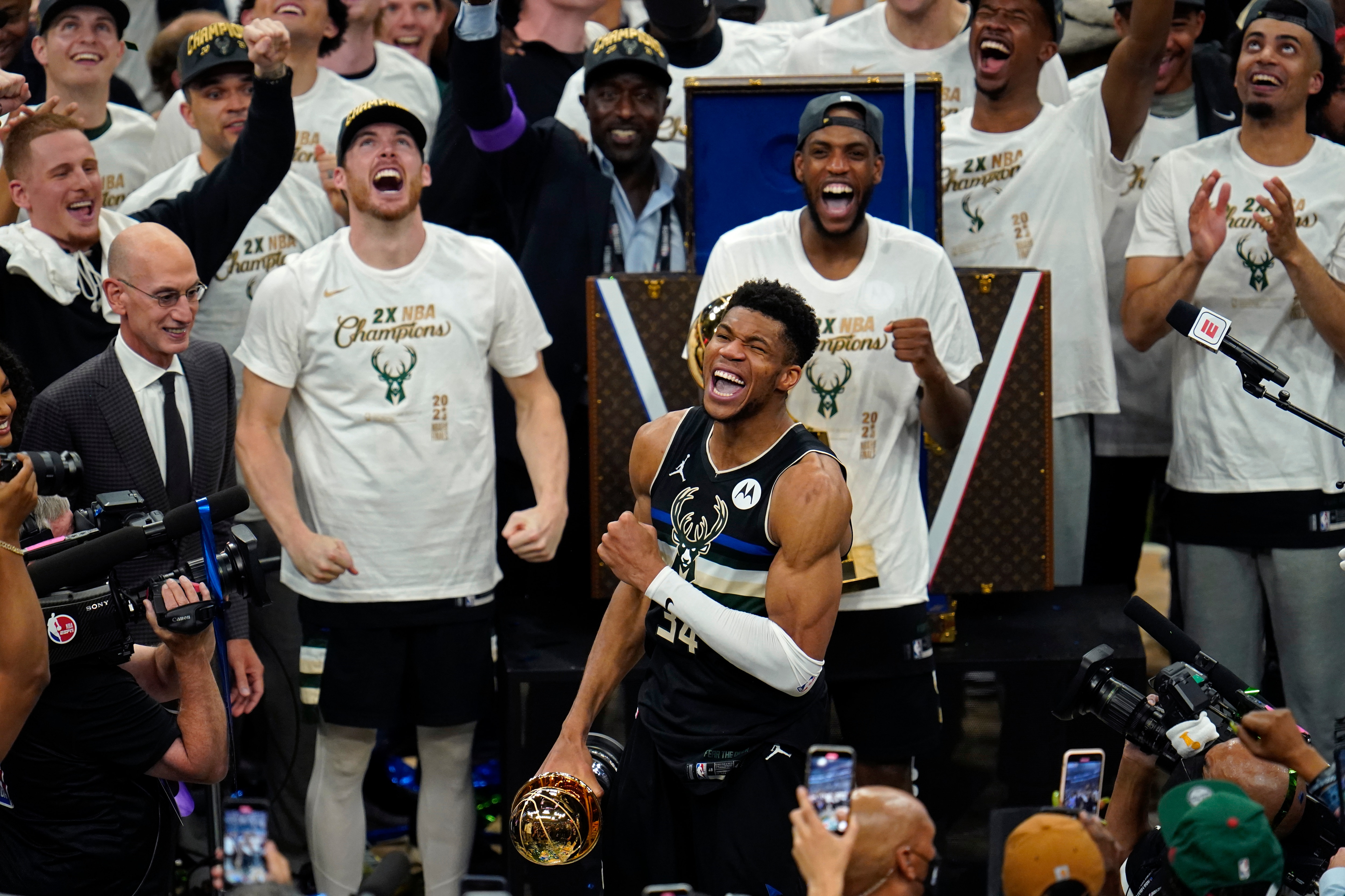 Milwaukee Bucks forward Giannis Antetokounmpo (34) reads with the championship trophy after defeating the Phoenix Suns in Game 6 of basketball's NBA Finals in Milwaukee, Tuesday, July 20, 2021. The Bucks won 105-98. (AP Photo/Paul Sancya)
