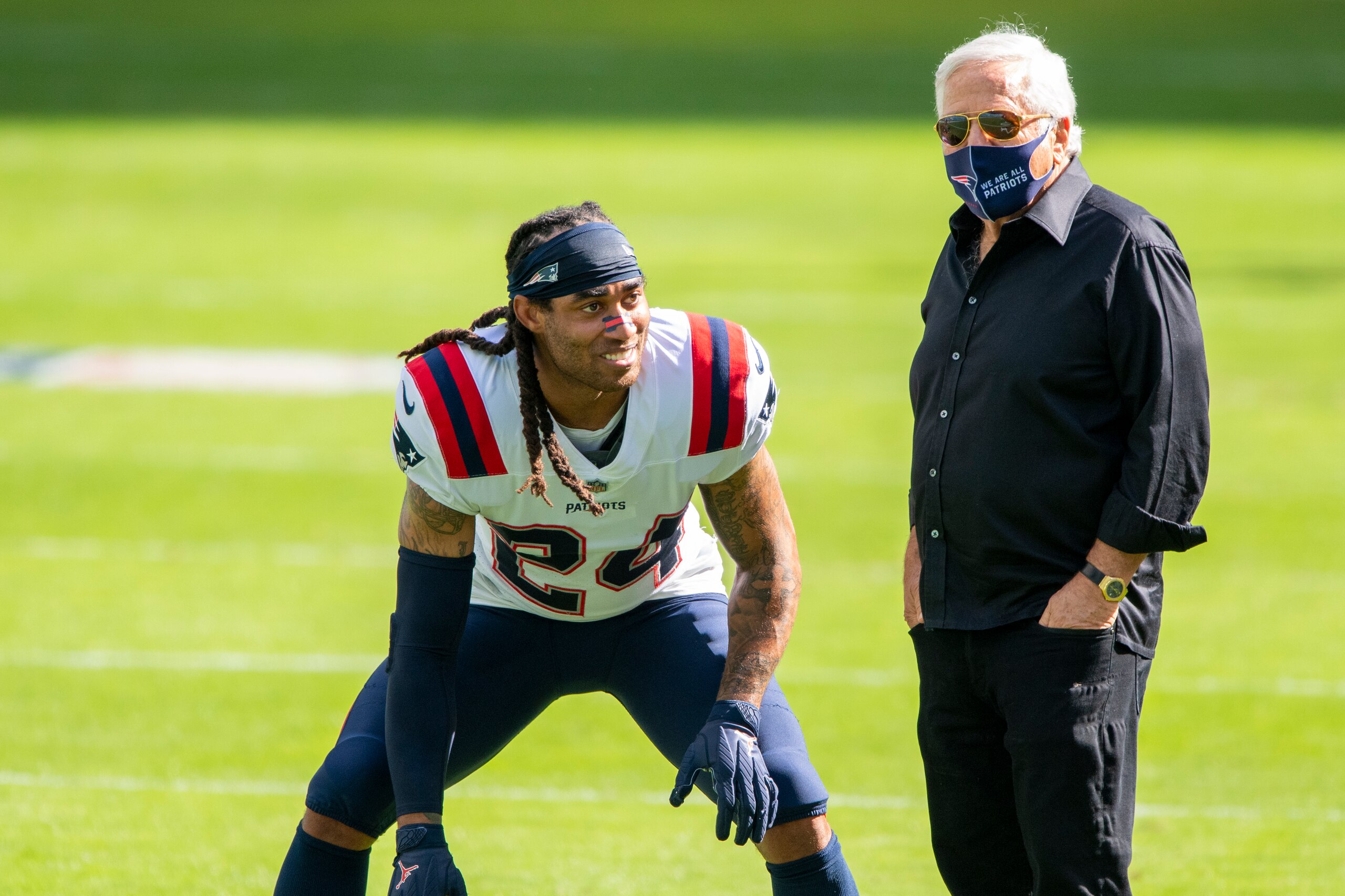 New England Patriots owner Robert Kraft wears a mask on the field as he talks with New England Patriots cornerback Stephon Gilmore (24) before the Patriots take on the Miami Dolphins during an NFL football game, Sunday, Dec. 20, 2020, in Miami Gardens, Fla. (AP Photo/Doug Murray)