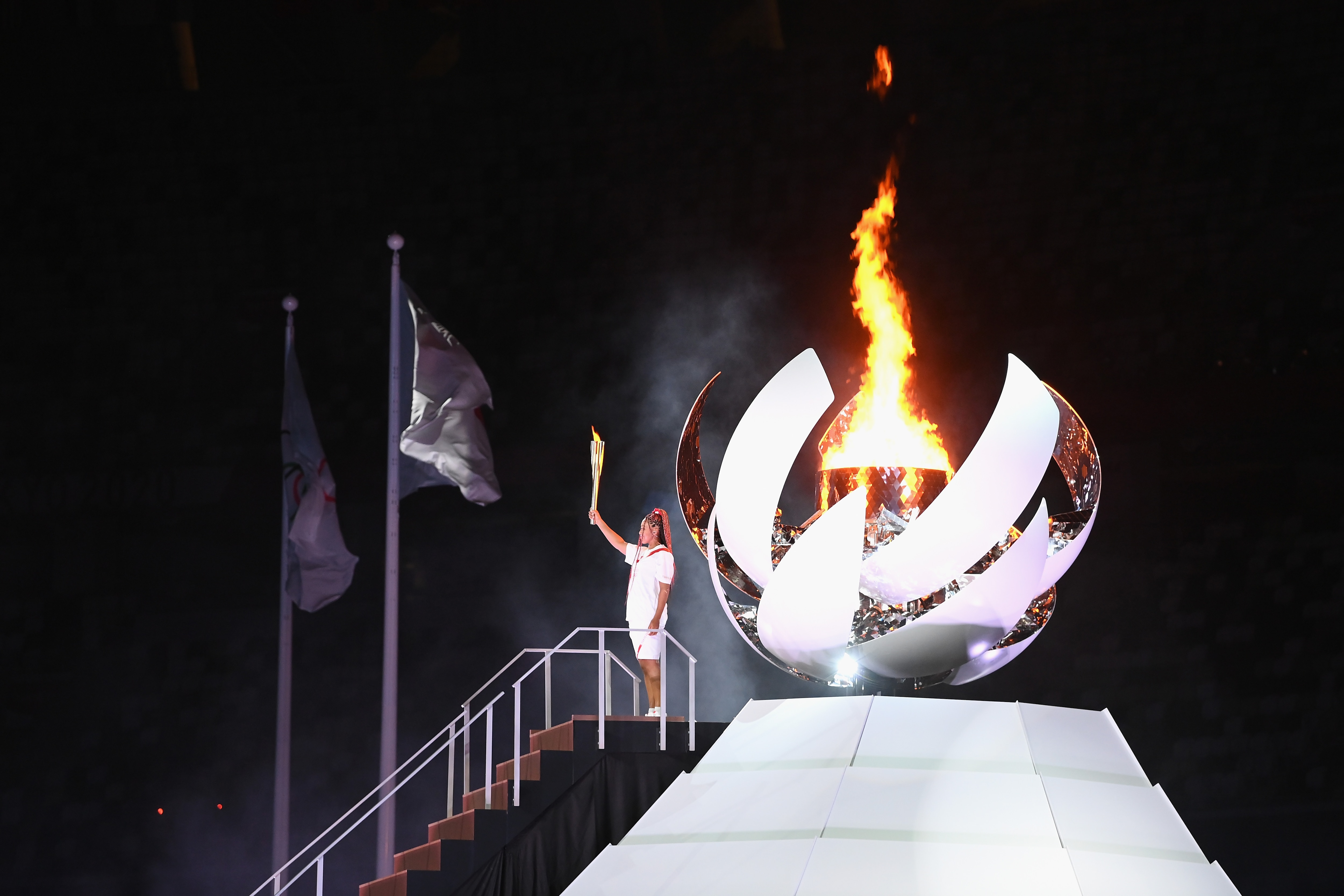 TOKYO, JAPAN - JULY 23: Naomi Osaka of Team Japan lights the Olympic cauldron with the Olympic torch during the Opening Ceremony of the Tokyo 2020 Olympic Games at Olympic Stadium on July 23, 2021 in Tokyo, Japan. (Photo by Matthias Hangst/Getty Images)