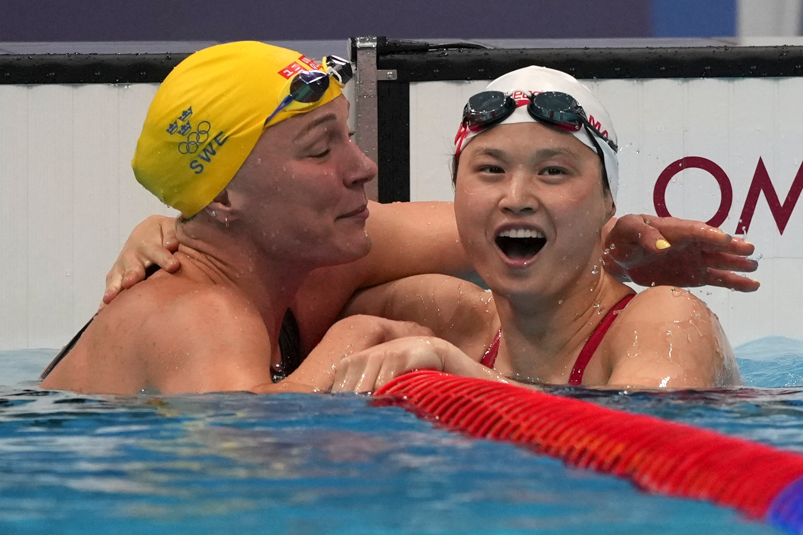 Margaret MacNeil, right, of Canada, is congratulated by Sarah Sjoestroem of Sweden after winning the final of the women's 100-meter butterfly at the 2020 Summer Olympics, Monday, July 26, 2021, in Tokyo, Japan. (AP Photo/Matthias Schrader)