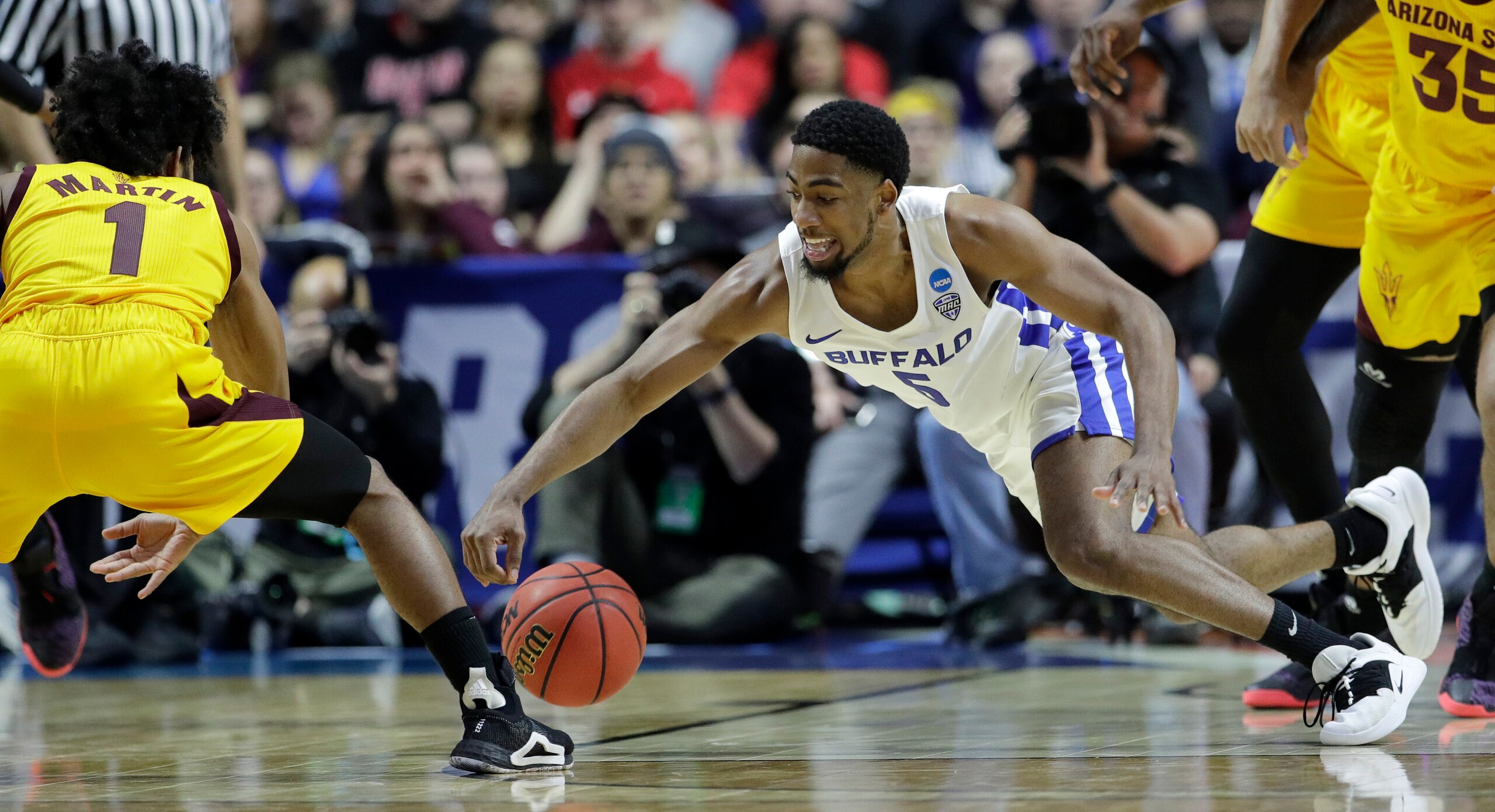 Buffalo's CJ Massinburg (5) and Arizona State's Luguentz Dort (1) chase a loose ball during the first half of a first round men's college basketball game in the NCAA Tournament Friday, March 22, 2019, in Tulsa, Okla. (AP Photo/Charlie Riedel)