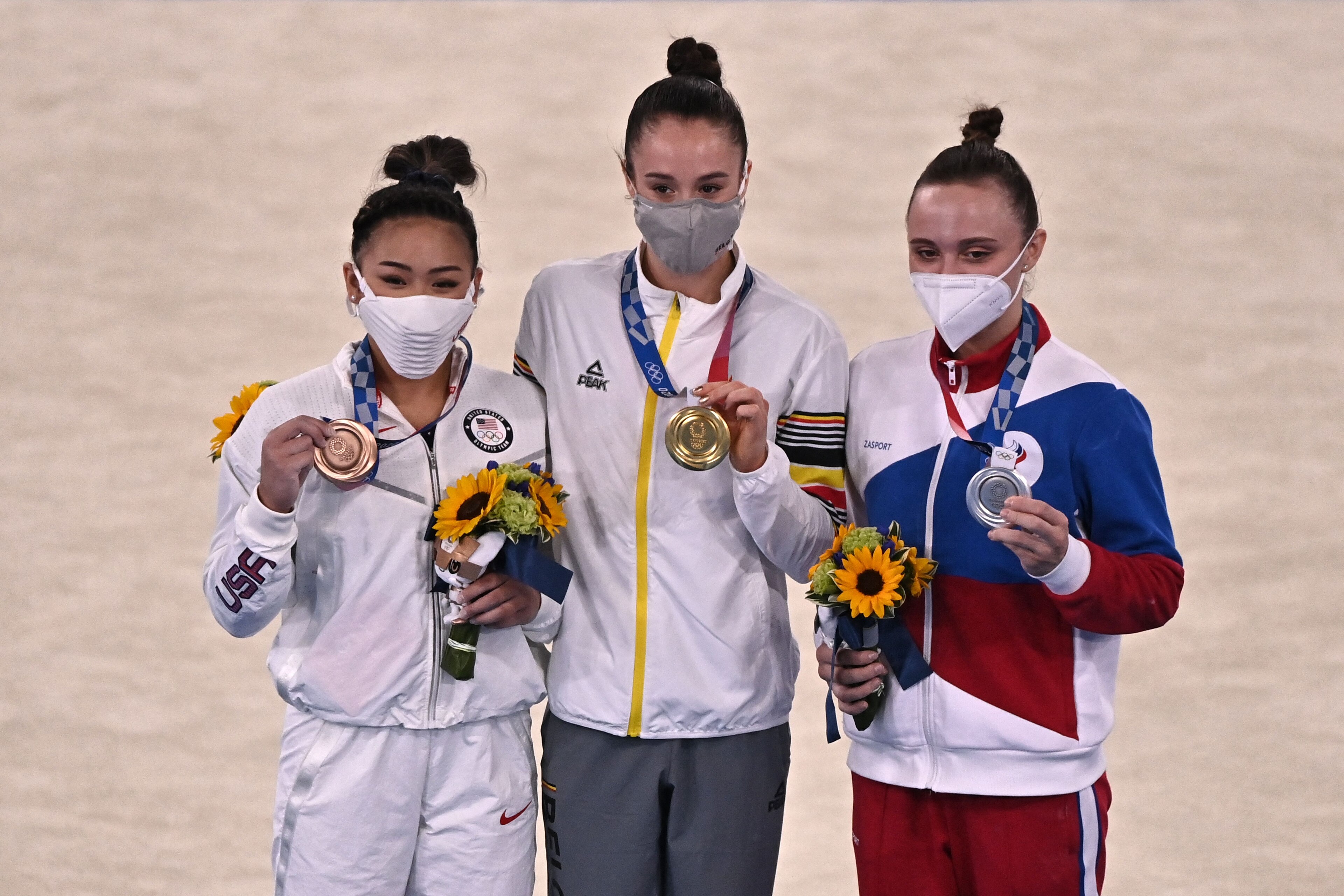 (From L) Bronze medallist USA's Sunisa Lee, gold medallist Belgium's Nina Derwael and silver medallist Russia's Anastasiia Iliankova pose on the podium of the artistic gymnastics women's uneven bars final of the Tokyo 2020 Olympic Games at the Ariake Gymnastics Centre in Tokyo on August 1, 2021. (Photo by Jeff PACHOUD / AFP) (Photo by JEFF PACHOUD/AFP via Getty Images) (From L) Bronze medallist USA's Sunisa Lee, gold medallist Belgium's Nina Derwael and silver medallist Russia's Anastasiia Iliankova pose on the podium of the artistic gymnastics women's uneven bars final of the Tokyo 2020 Olympic Games at the Ariake Gymnastics Centre in Tokyo on August 1, 2021. (Photo by Jeff PACHOUD / AFP) (Photo by JEFF PACHOUD/AFP via Getty Images)
