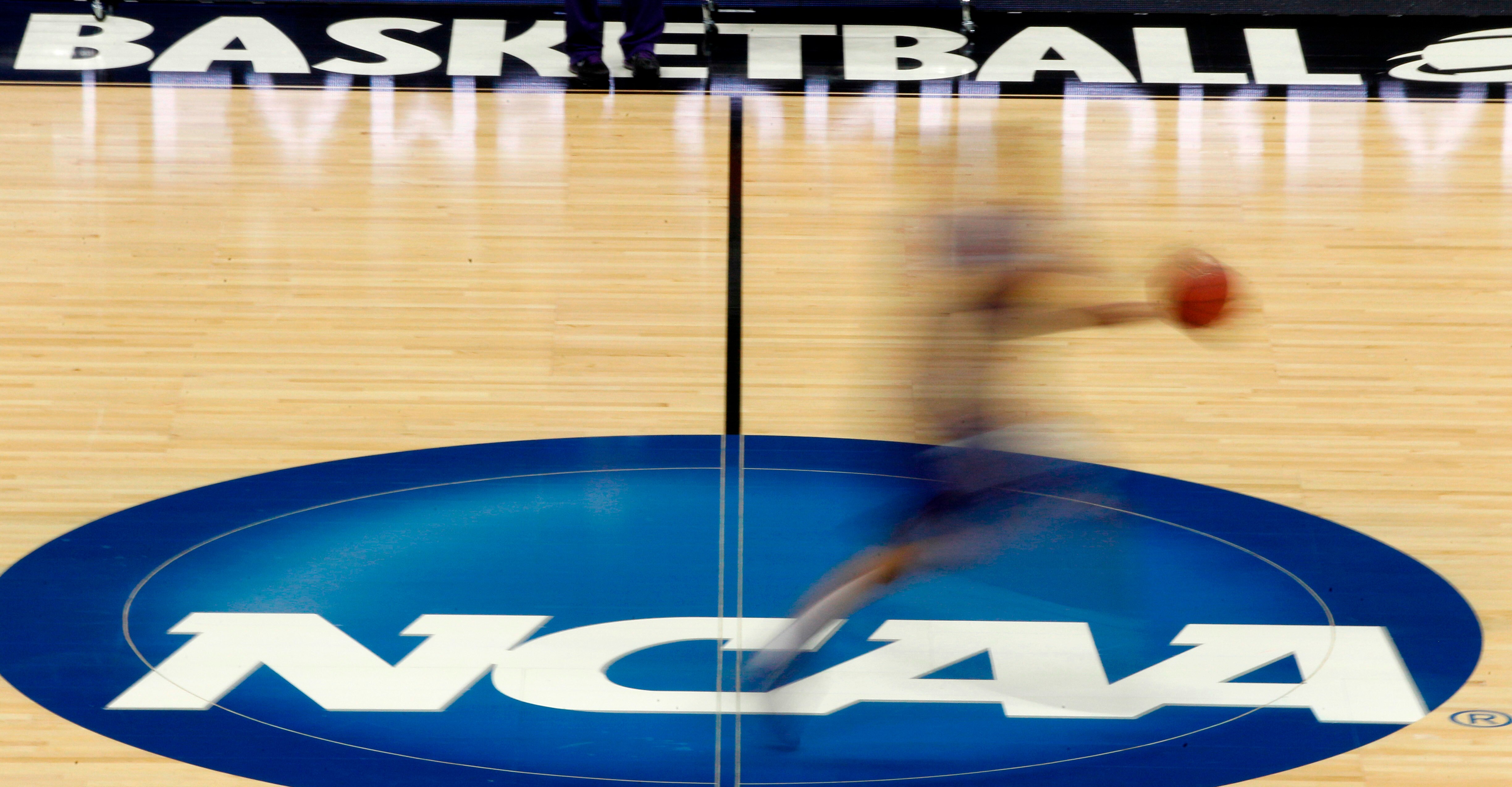 FILE - In this March 14, 2012, file photo, a player runs across the NCAA logo during practice in Pittsburgh. Widespread testing for the new coronavirus will be crucial to having college sports in the fall, especially contact sports such as football and basketball, the NCAA's chief medical officer said, Friday, May 1, 2020. (AP Photo/Keith Srakocic, File)