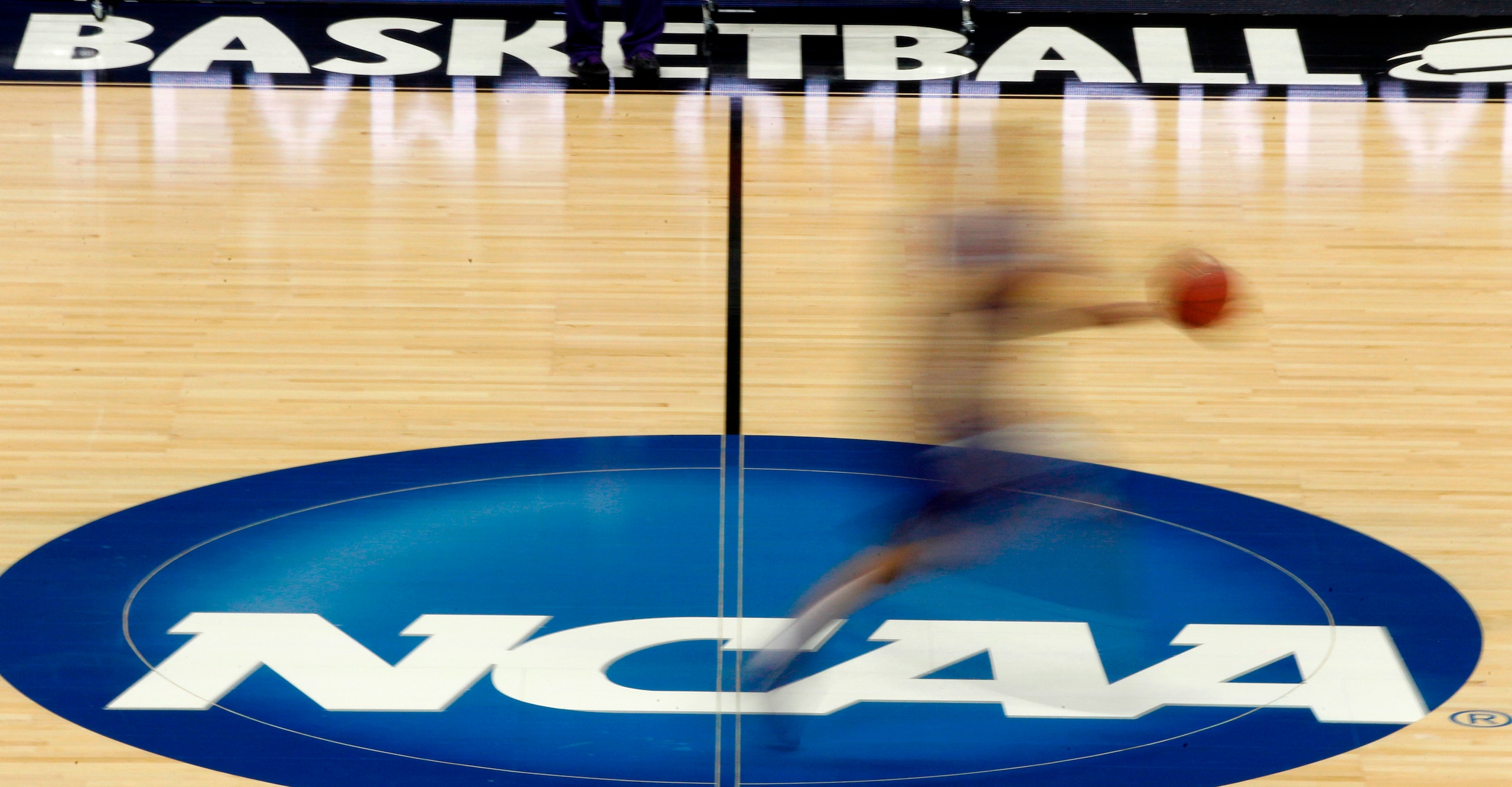 FILE - In this March 14, 2012, file photo, a player runs across the NCAA logo during practice in Pittsburgh. Widespread testing for the new coronavirus will be crucial to having college sports in the fall, especially contact sports such as football and basketball, the NCAA's chief medical officer said, Friday, May 1, 2020. (AP Photo/Keith Srakocic, File)