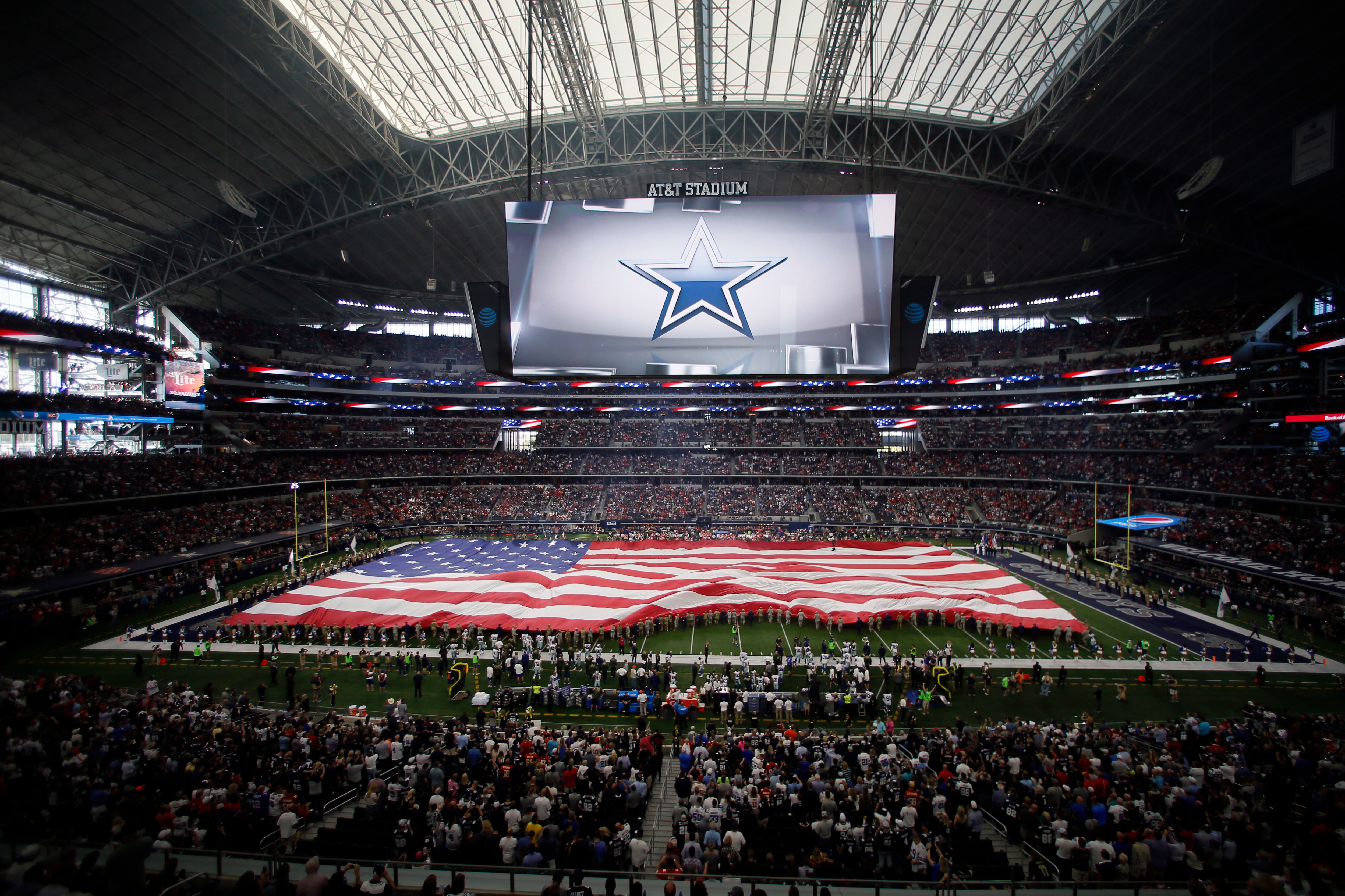 In this general, overall, view, a field-sized American flag is displayed with the Dallas Cowboys logo projected on the large video screen during the playing of the national anthem at AT&T Stadium before an NFL football game against the Kansas City Chiefs on Sunday, Nov. 5, 2017, in Arlington, Texas. (AP Photo/Roger Steinman)