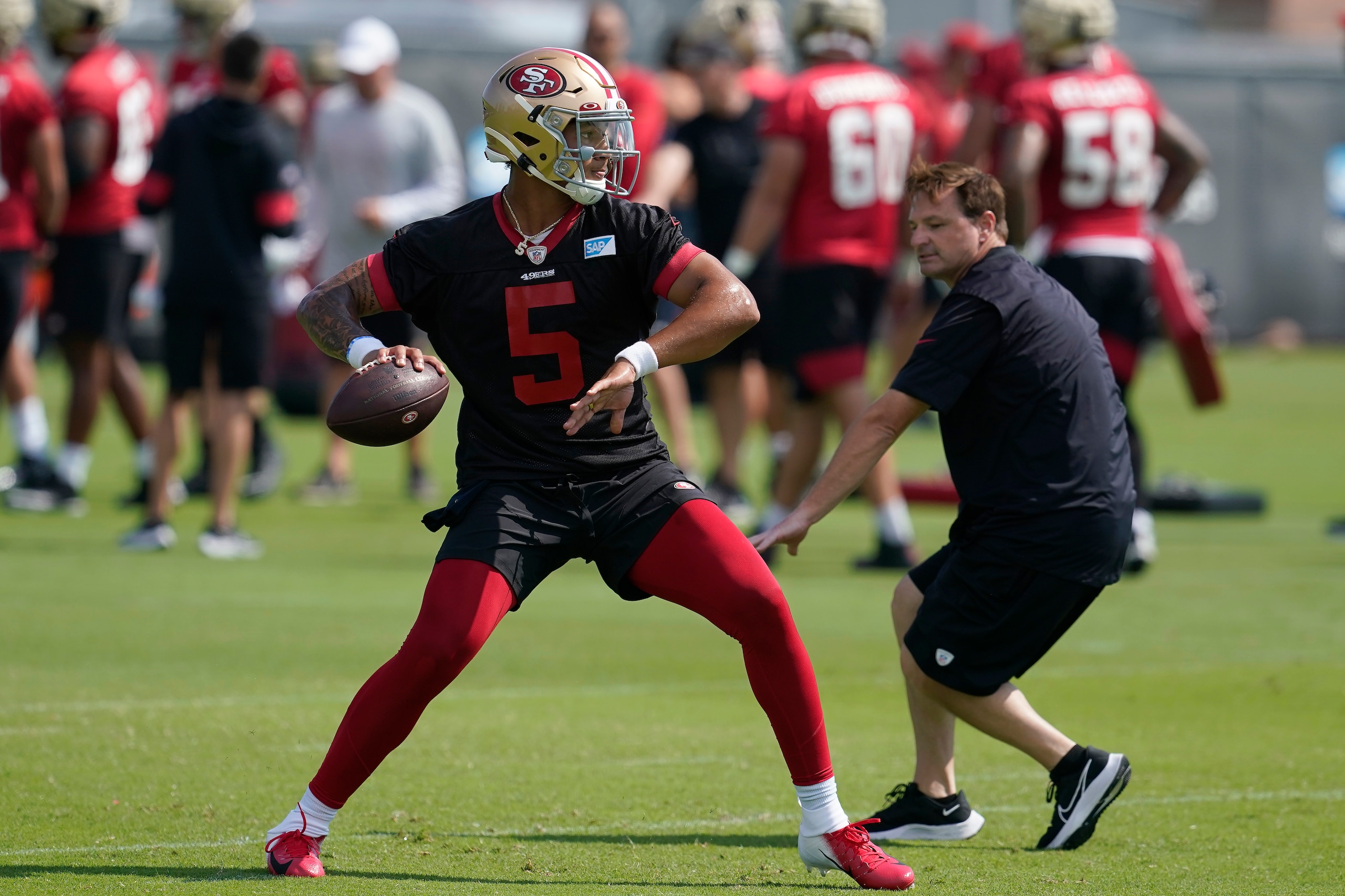 San Francisco 49ers quarterback Trey Lance throws a pass in front of quarterbacks coach Rich Scangarello at NFL football training camp in Santa Clara, Calif., Thursday, July 29, 2021. (AP Photo/Jeff Chiu) San Francisco 49ers quarterback Trey Lance throws a pass in front of quarterbacks coach Rich Scangarello at NFL football training camp in Santa Clara, Calif., Thursday, July 29, 2021. (AP Photo/Jeff Chiu)