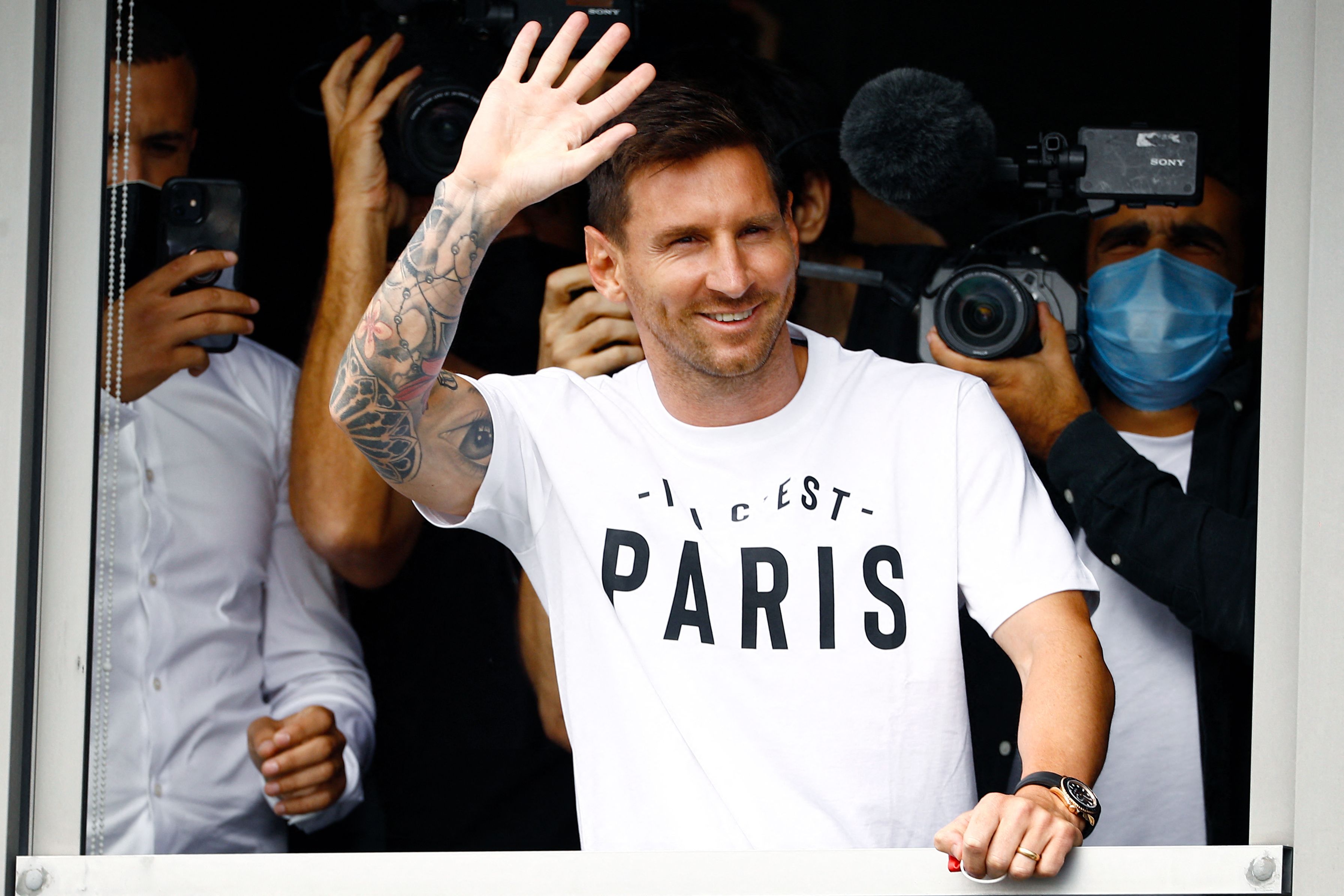 TOPSHOT - Argentinian football player Lionel Messi waves to supporters from a window after he landed on August 10, 2021 at Le Bourget airport, north of Paris, to become Paris Saint-Germain's new player following his departure from Barcelona, the club he has represented for the entirety of his 17-year professional career so far. - Asked by reporters at Barcelona's El Prat airport if the Argentine star would later on sign with the French club, Jorge Messi, the father and player's agent, said: "Yes". (Photo by Sameer Al-DOUMY / AFP) (Photo by SAMEER AL-DOUMY/AFP via Getty Images)