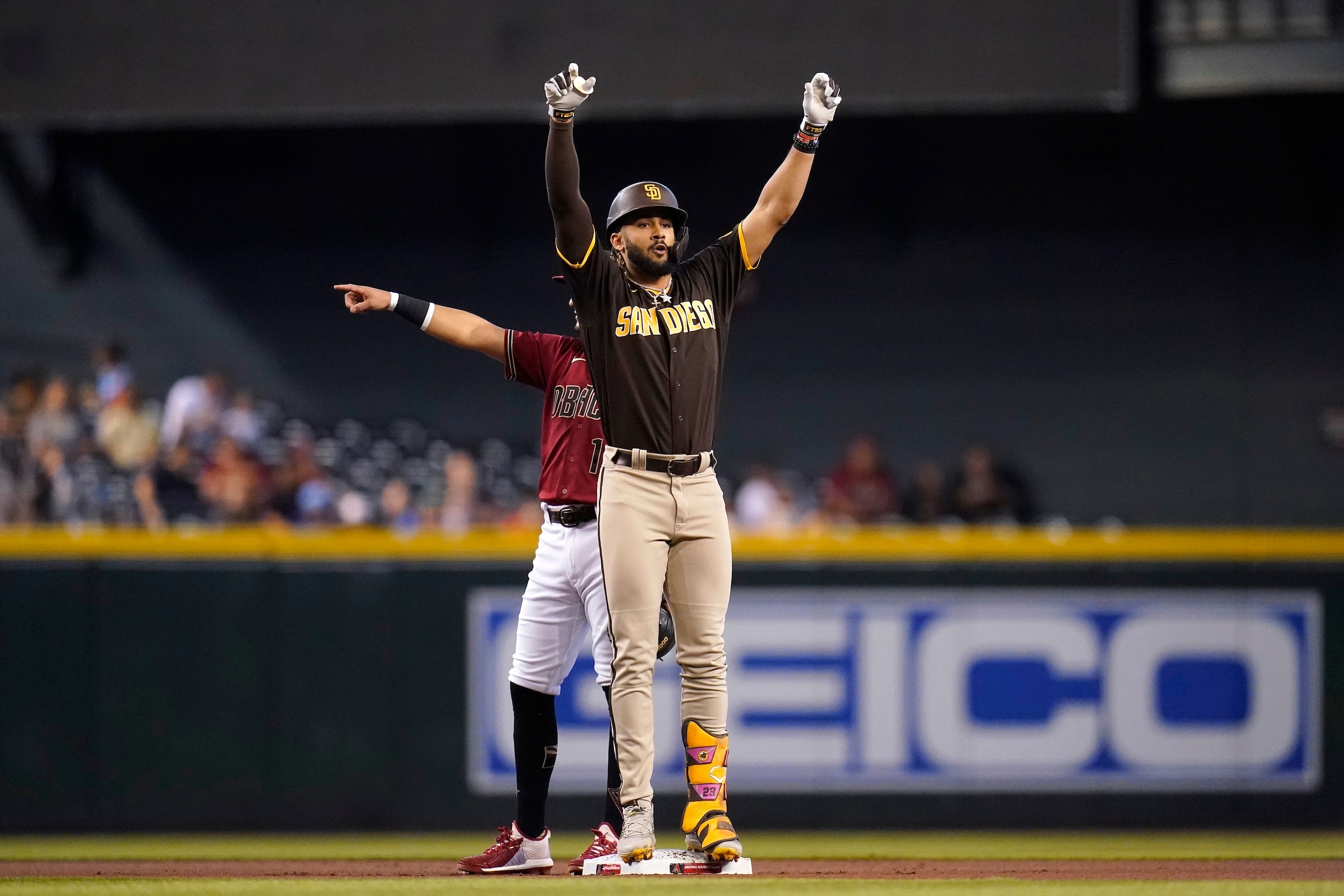 San Diego Padres' Fernando Tatis Jr., front, stands on second base as he celebrates his double and Arizona Diamondbacks second baseman Josh Rojas, back, points to a teammate during the first inning of a baseball game, Sunday, Aug. 15, 2021, in Phoenix. (AP Photo/Ross D. Franklin)