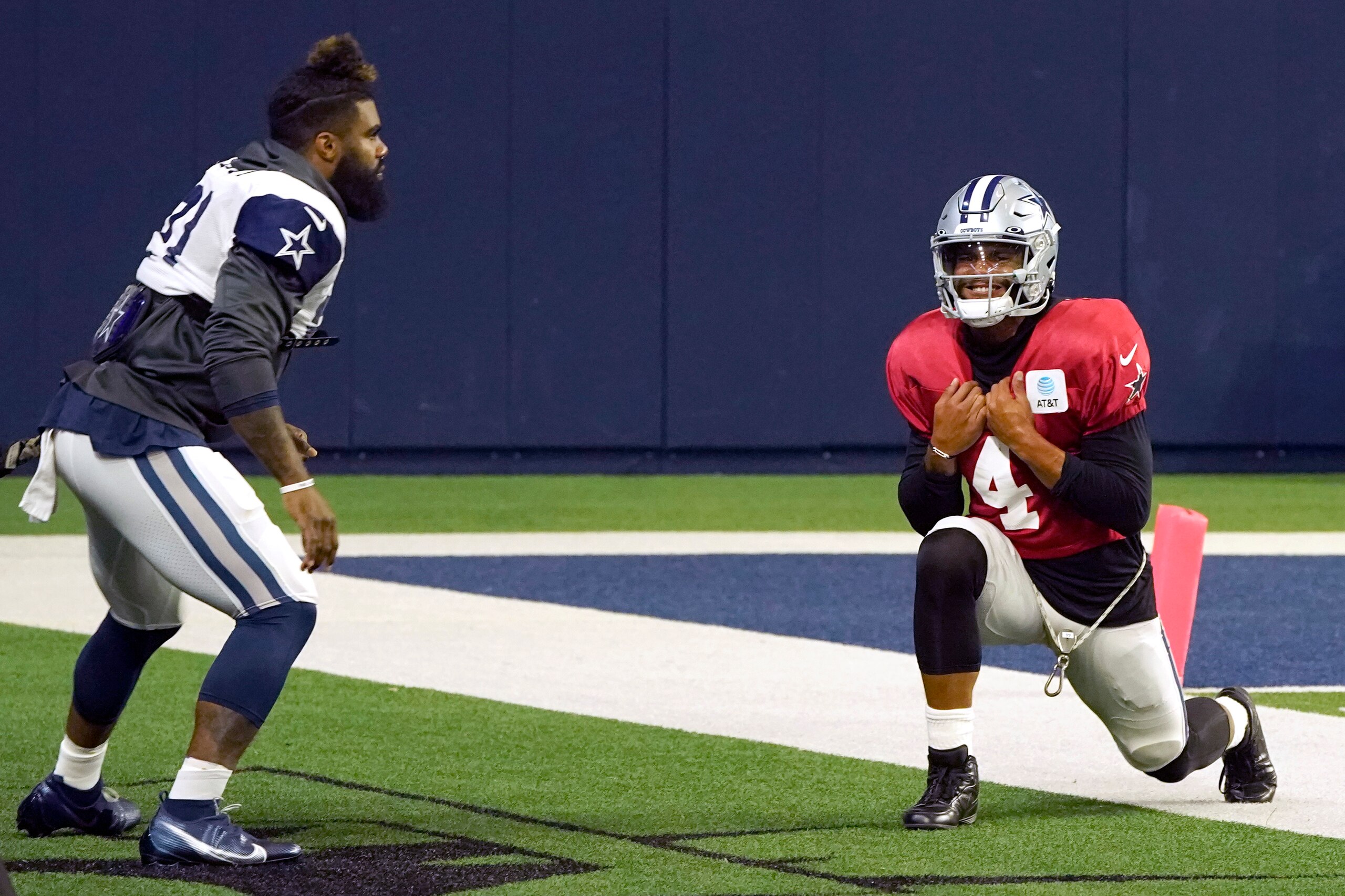 Dallas Cowboys quarterback Dak Prescott (4) stretches with teammate running back Ezekiel Elliott (21) during an NFL football practice in Frisco, Texas, Monday, Aug. 16, 2021. (AP Photo/LM Otero)