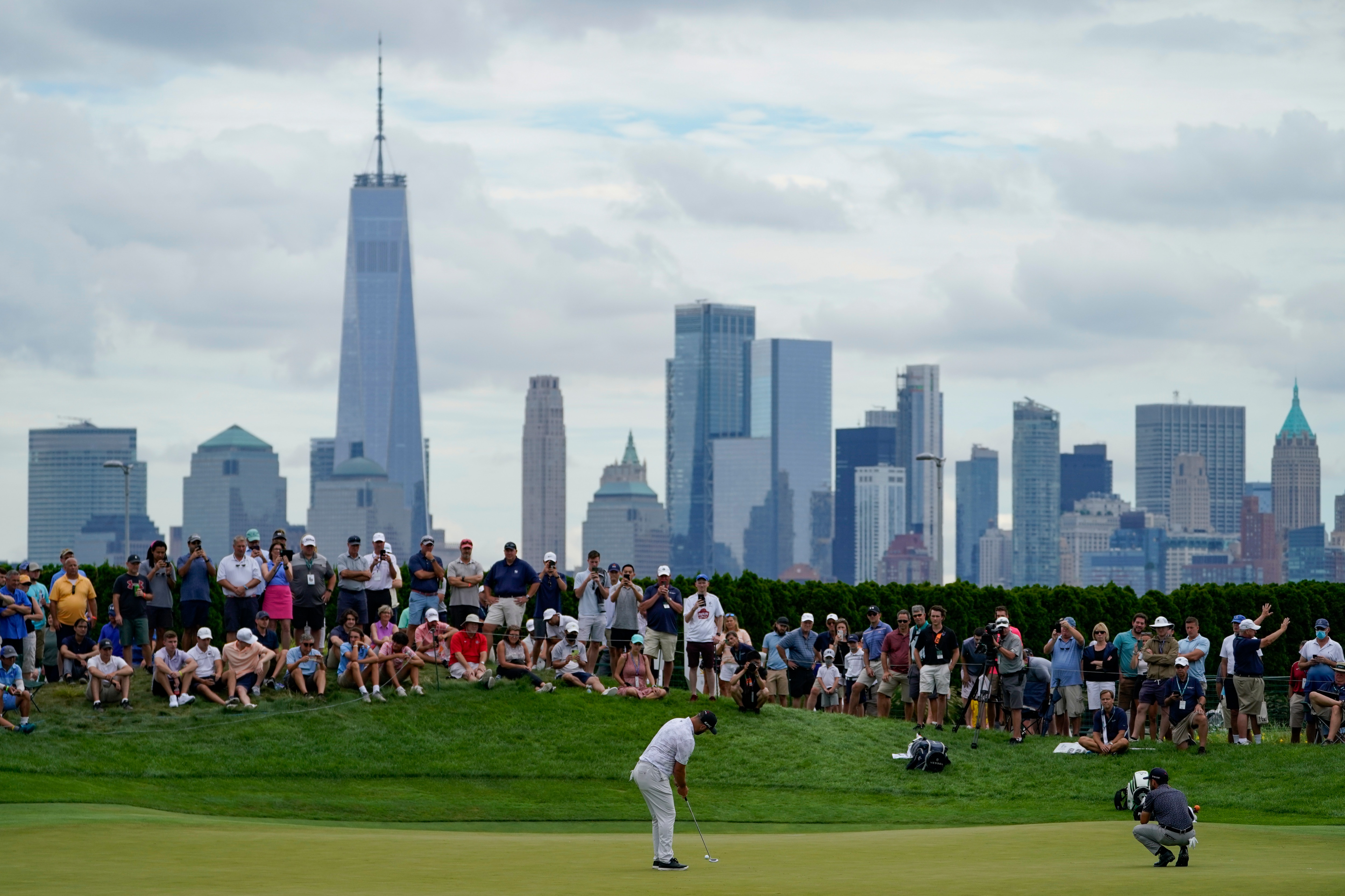 Jon Rahm, of Spain, putts on the 18th green as the Manhattan skyline looms in the distance in the second round at the Northern Trust golf tournament, Friday, Aug. 20, 2021, at Liberty National Golf Course in Jersey City, N.J. (AP Photo/John Minchillo)