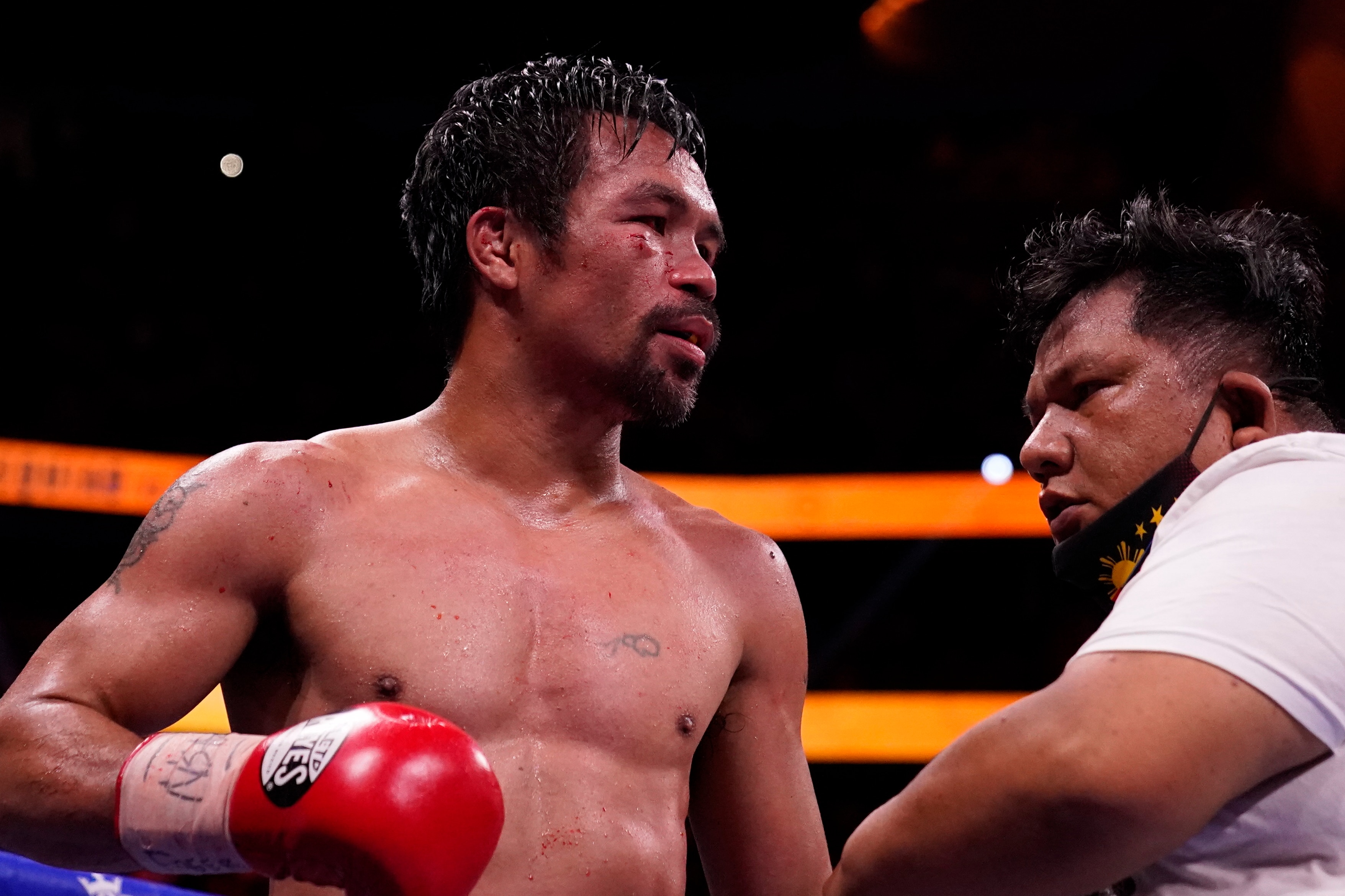 Manny Pacquiao, of the Philippines, waits in the ring with a trainer after losing his fight to Yordenis Ugas, of Cuba, in a welterweight championship boxing match Saturday, Aug. 21, 2021, in Las Vegas. (AP Photo/John Locher)