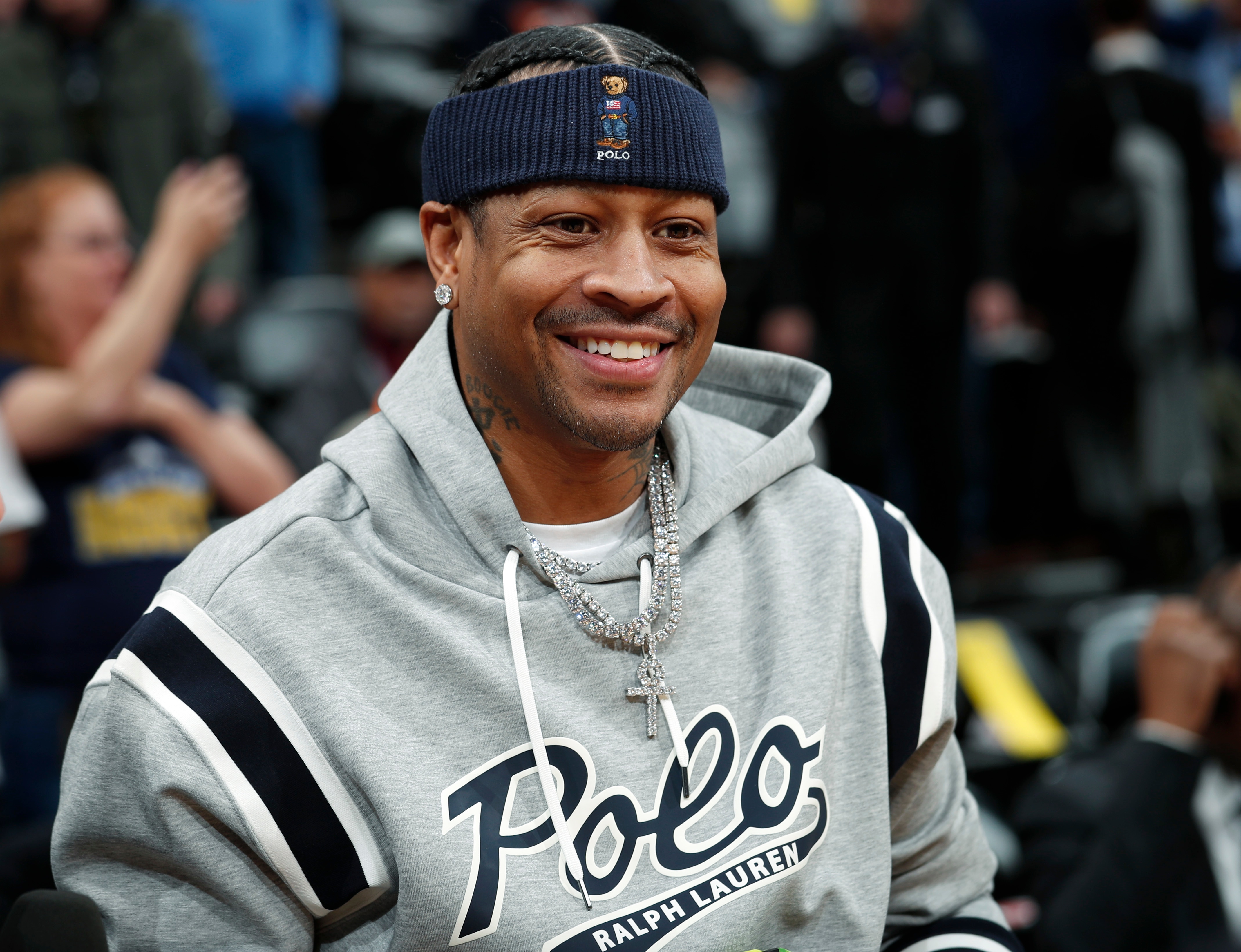 Retired Denver Nuggets guard Allen Iverson smiles as he jokes with fans before taking a seat to watch the Nuggets play the San Antonio Spurs in an NBA basketball game Friday, Feb. 23, 2018, in Denver. Iverson joined former teammates Kenyon Martin and Marcus Camby to be honored by the team during a ceremony at halftime. (AP Photo/David Zalubowski)