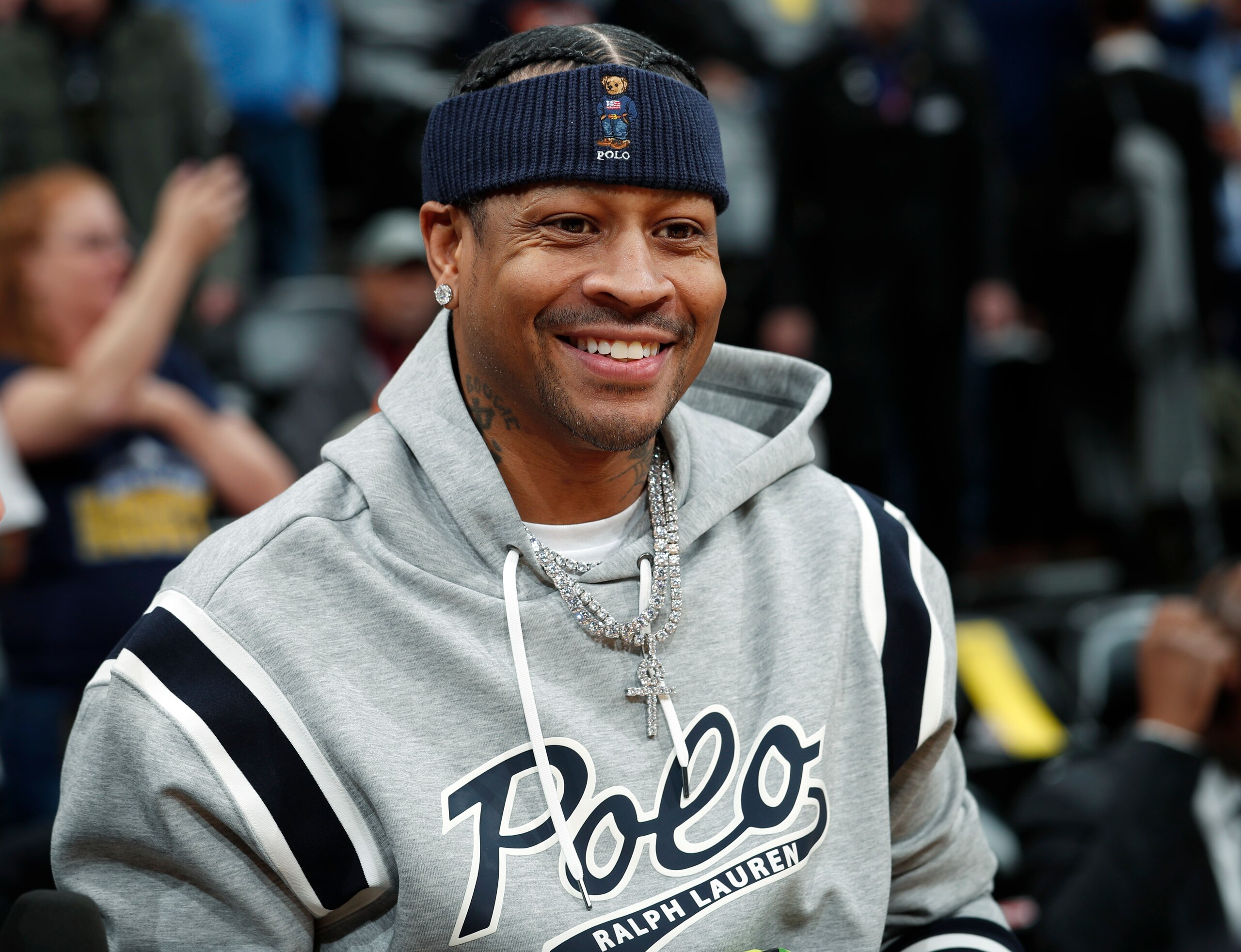 Retired Denver Nuggets guard Allen Iverson smiles as he jokes with fans before taking a seat to watch the Nuggets play the San Antonio Spurs in an NBA basketball game Friday, Feb. 23, 2018, in Denver. Iverson joined former teammates Kenyon Martin and Marcus Camby to be honored by the team during a ceremony at halftime. (AP Photo/David Zalubowski)