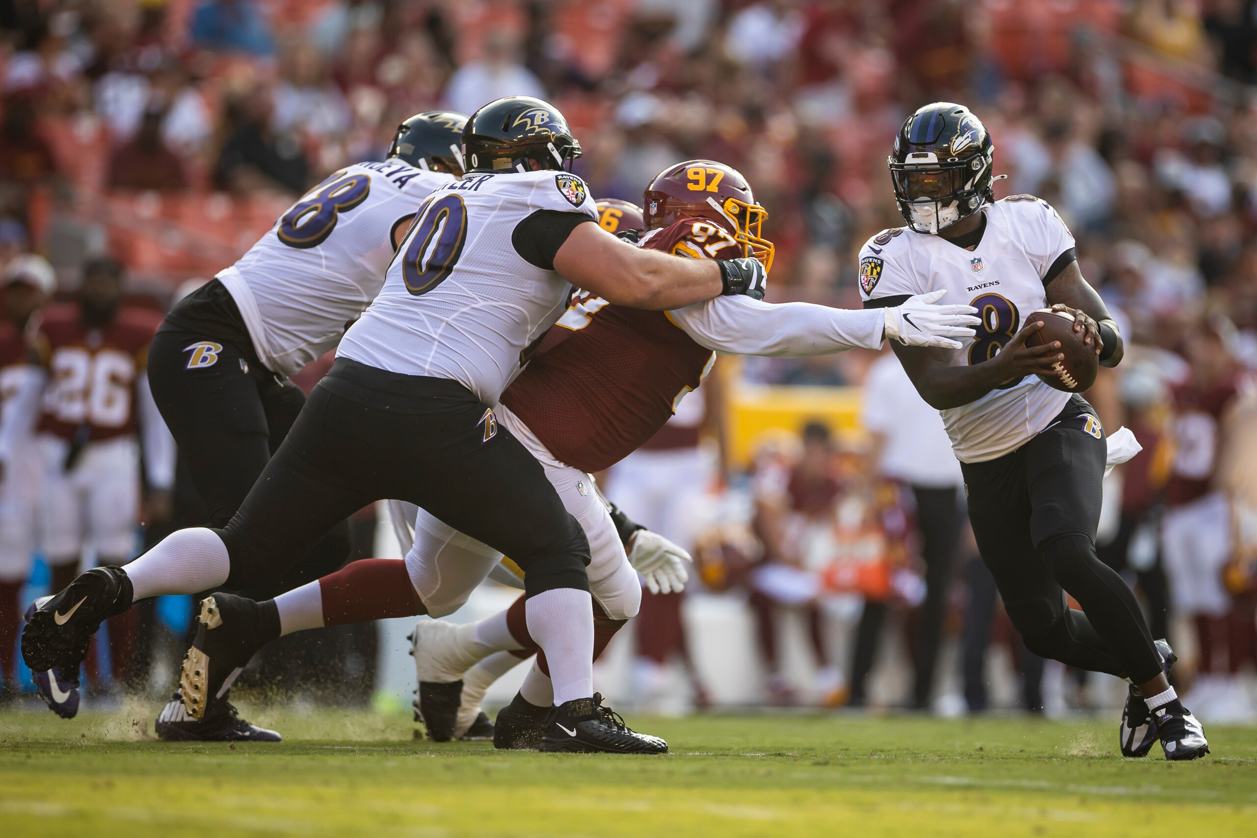 LANDOVER, MD - AUGUST 28: Lamar Jackson #8 of the Baltimore Ravens scrambles under pressure by Tim Settle #97 of the Washington Football Team during the first half of a preseason game at FedExField on August 28, 2021 in Landover, Maryland. (Photo by Scott Taetsch/Getty Images)