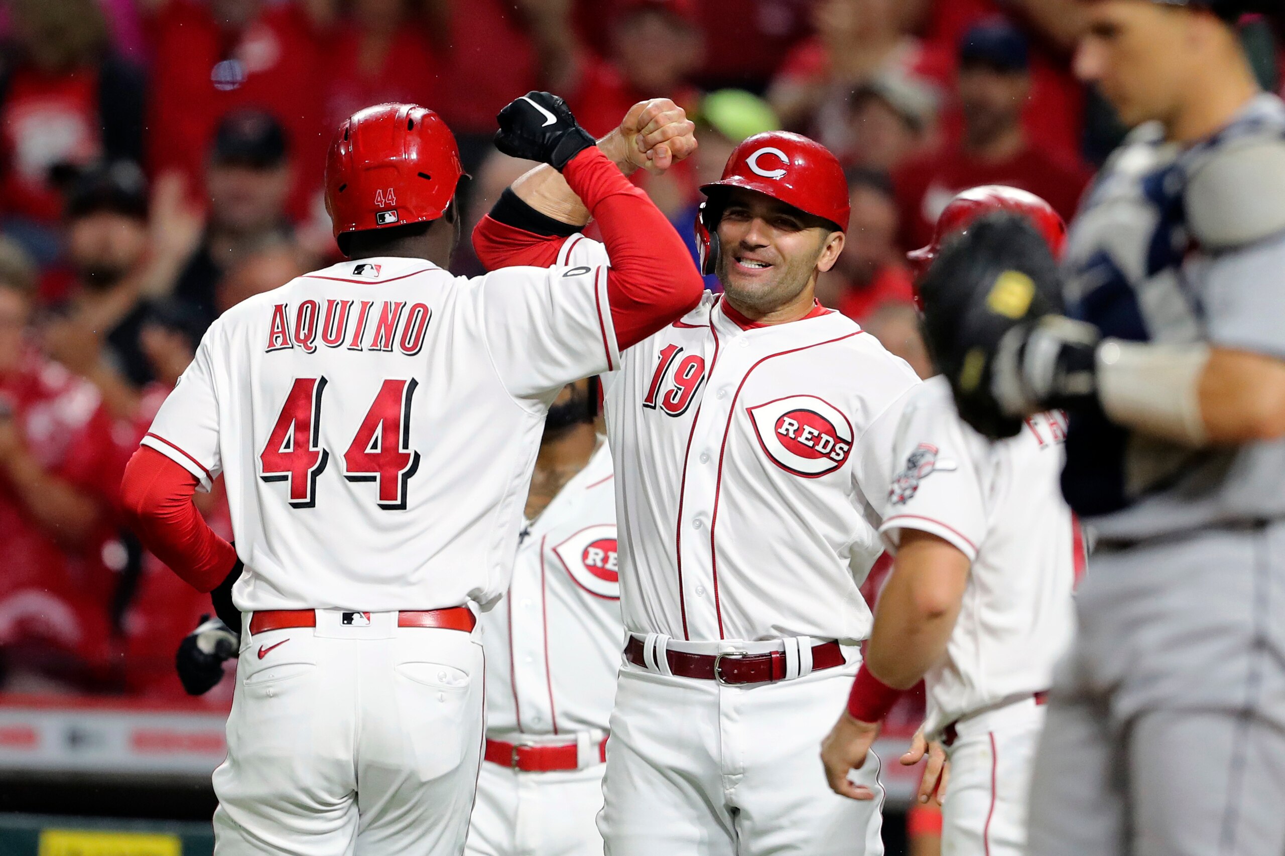 Cincinnati Reds' Aristides Aquino (44) bumps arms with Joey Votto (19) after Aquino crossing the plate with a three-run home run off Detroit Tigers starting pitcher Matthew Boyd during the third inning of a baseball game, Saturday, Sept. 4, 2021, in Cincinnati. (AP Photo/Gary Landers)
