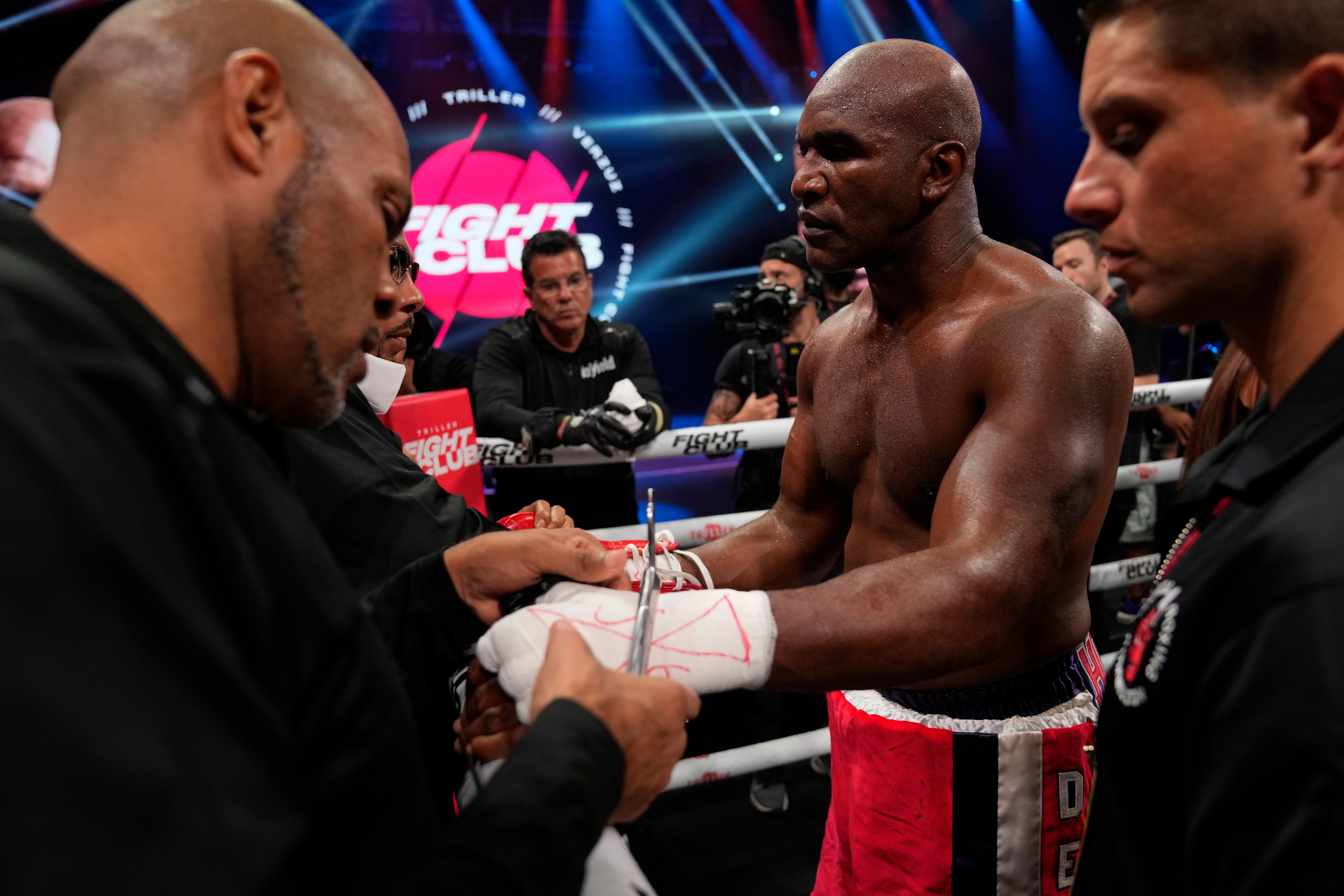 Former heavyweight champion Evander Holyfield, center, has his gloves and hand wraps removed after losing in the first round of a boxing match against former MMA star Vitor Belfort, Saturday, Sept. 11, 2021, in Hollywood, Fla. (AP Photo/Rebecca Blackwell)
