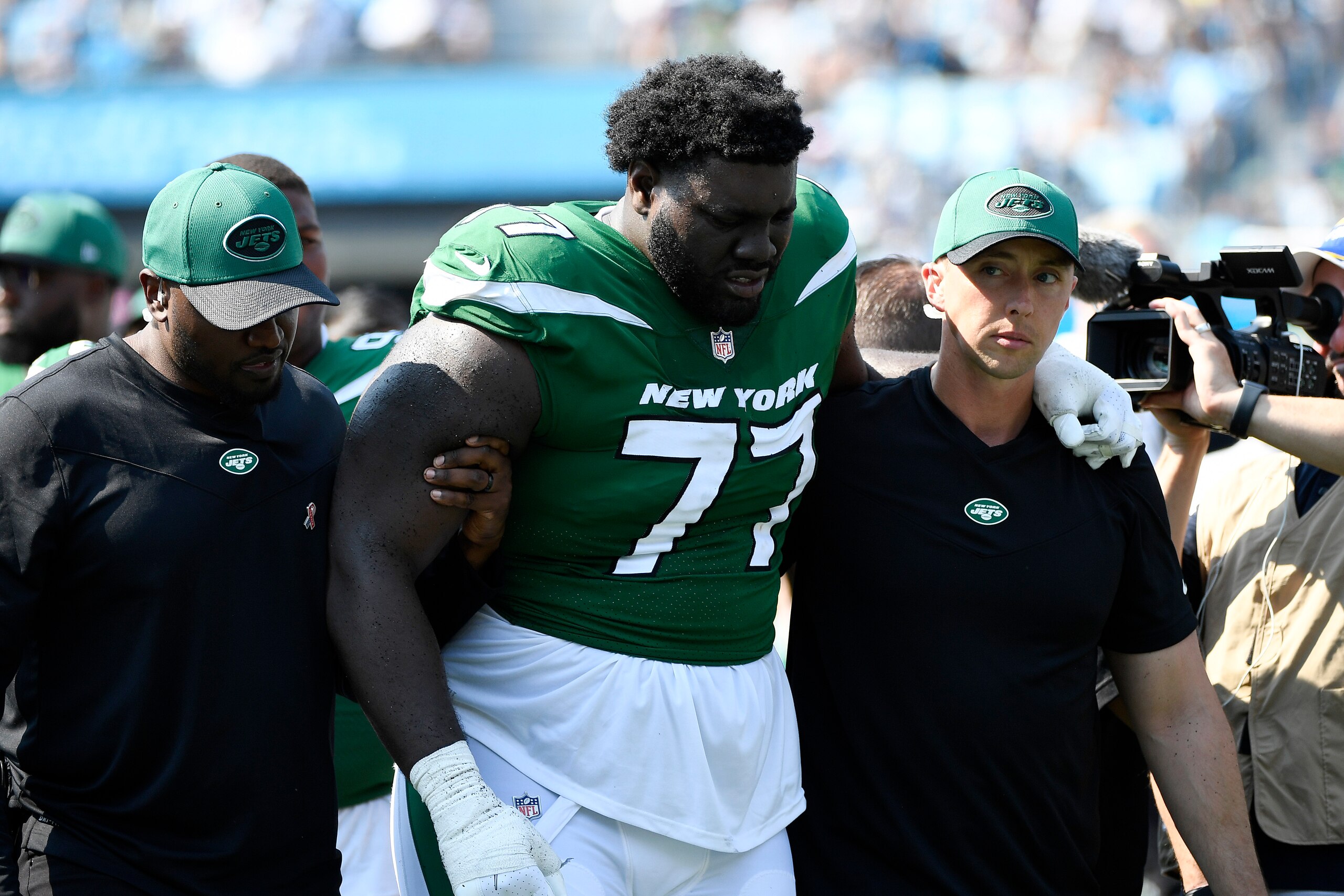 CHARLOTTE, NORTH CAROLINA - SEPTEMBER 12: Mekhi Becton #77 of the New York Jets is helped off the field after being injured during the third quarter against the Carolina Panthers at Bank of America Stadium on September 12, 2021 in Charlotte, North Carolina. (Photo by Mike Comer/Getty Images)