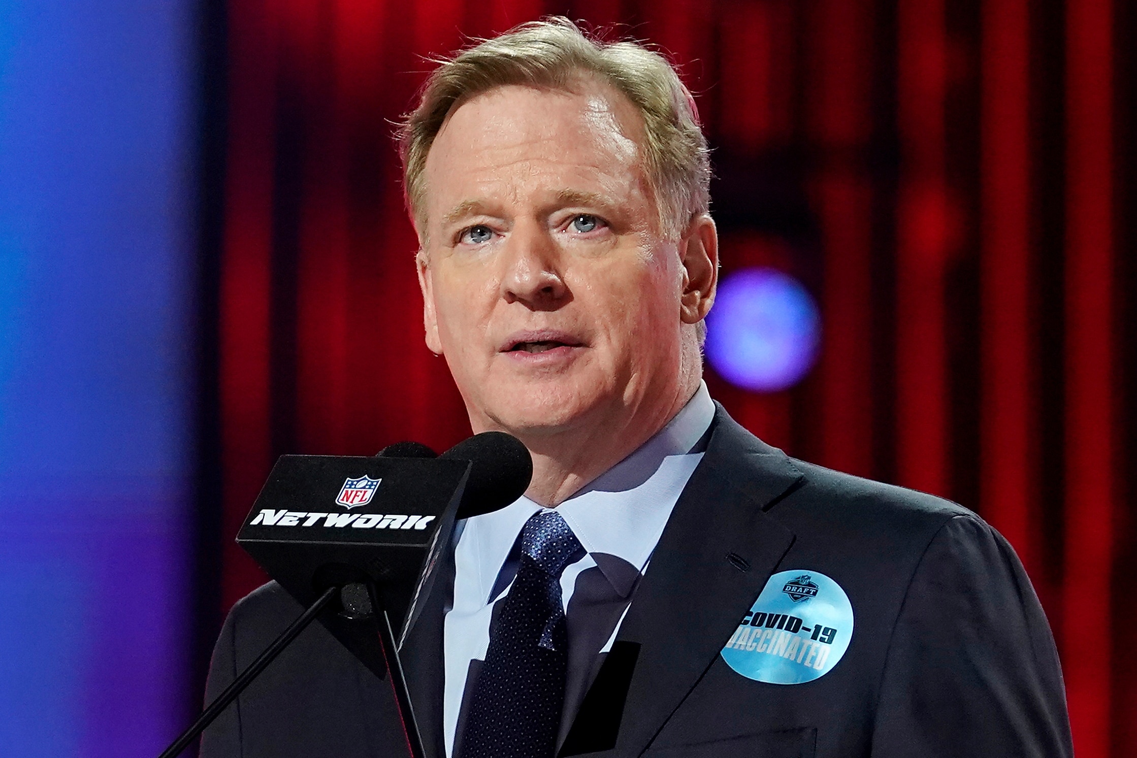 FILE - In this April 29, 2021, file photo, NFL commissioner Roger Goodell, wearing a COVID-19 vaccinated sticker, speaks during the first round of the NFL football draft in Cleveland. The NFL has informed teams they could potentially forfeit a game due to a COVID-19 outbreak among non-vaccinated players and players on both teams wouldn’t get paid that week. Commissioner Goodell said Thursday, July 22, 2021, in a memo sent to clubs that was obtained by The Associated Press that the league doesn’t anticipate adding a 19th week to accommodate games that can’t be rescheduled within the 18-week regular season. (AP Photo/Steve Luciano)