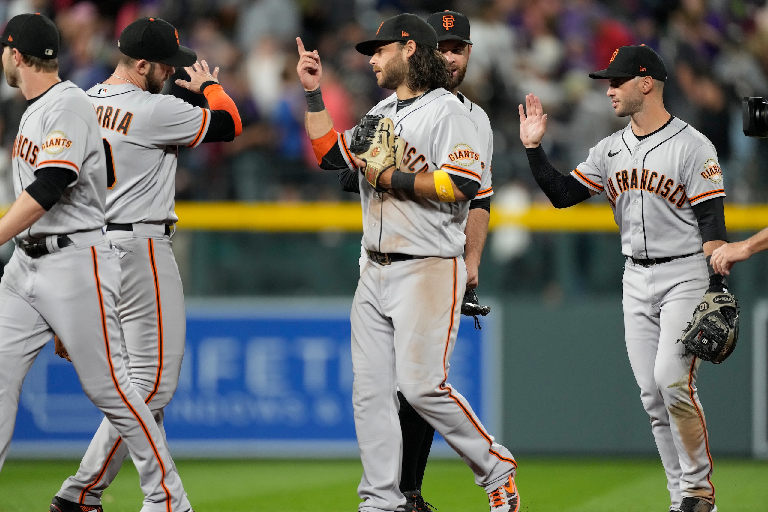 San Francisco Giants shortstop Brandon Crawford, front center, celebrates with from left, third baseman Evan Longoria, first baseman Brandon Belt and second baseman Tommy La Stella after the ninth inning of a baseball game against the Colorado Rockies Friday, Sept. 24, 2021, in Denver. The Giants won 7-2. (AP Photo/David Zalubowski)