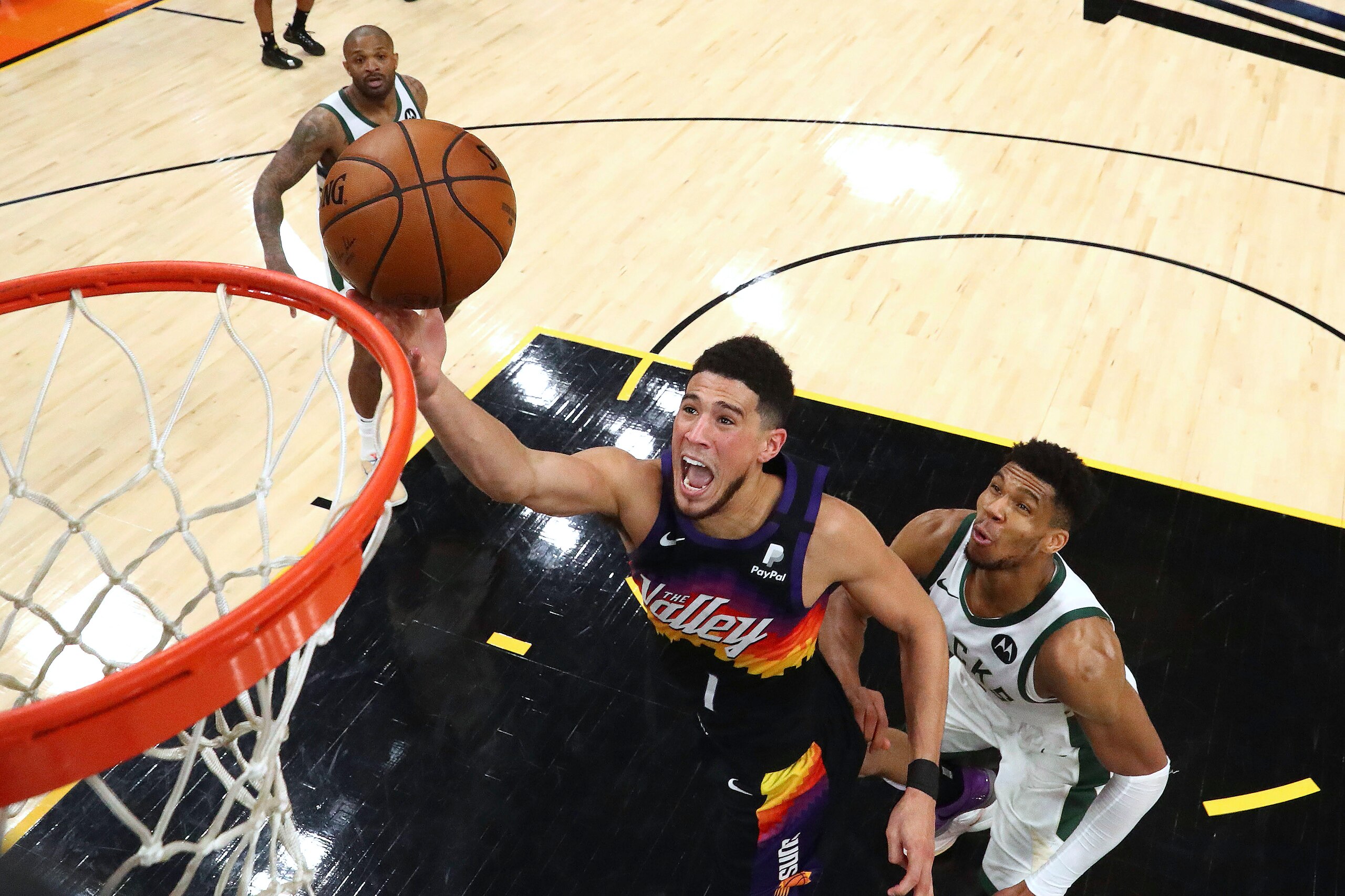 FILE - In this Saturday, July 17, 2021, file photo, Phoenix Suns guard Devin Booker (1) shoots past Milwaukee Bucks forward Giannis Antetokounmpo, right, during the second half of Game 5 of basketball's NBA Finals, in Phoenix. On Sunday, Sept. 26, 2021, the Suns announced that Booker will miss the start of training camp after being placed in the league's health and safety protocol. (Mark J. Rebilas/Pool Photo via AP, File)