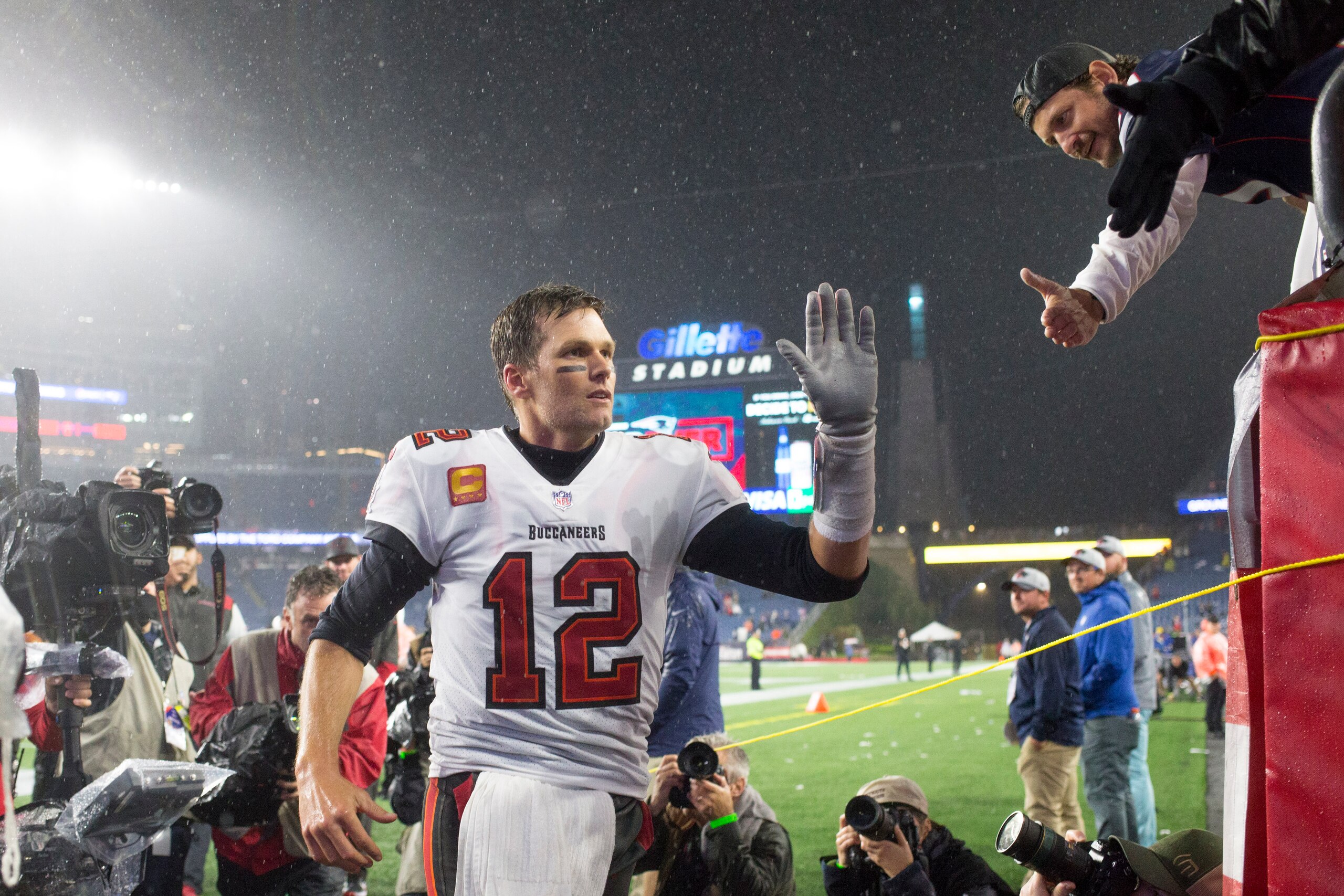 Tampa Bay Buccaneers quarterback Tom Brady (12) greets a fan after defeating the New England Patriots in an NFL football game, Sunday, Oct. 3, 2021, in Foxborough, Mass. (AP Photo/Greg M. Cooper)