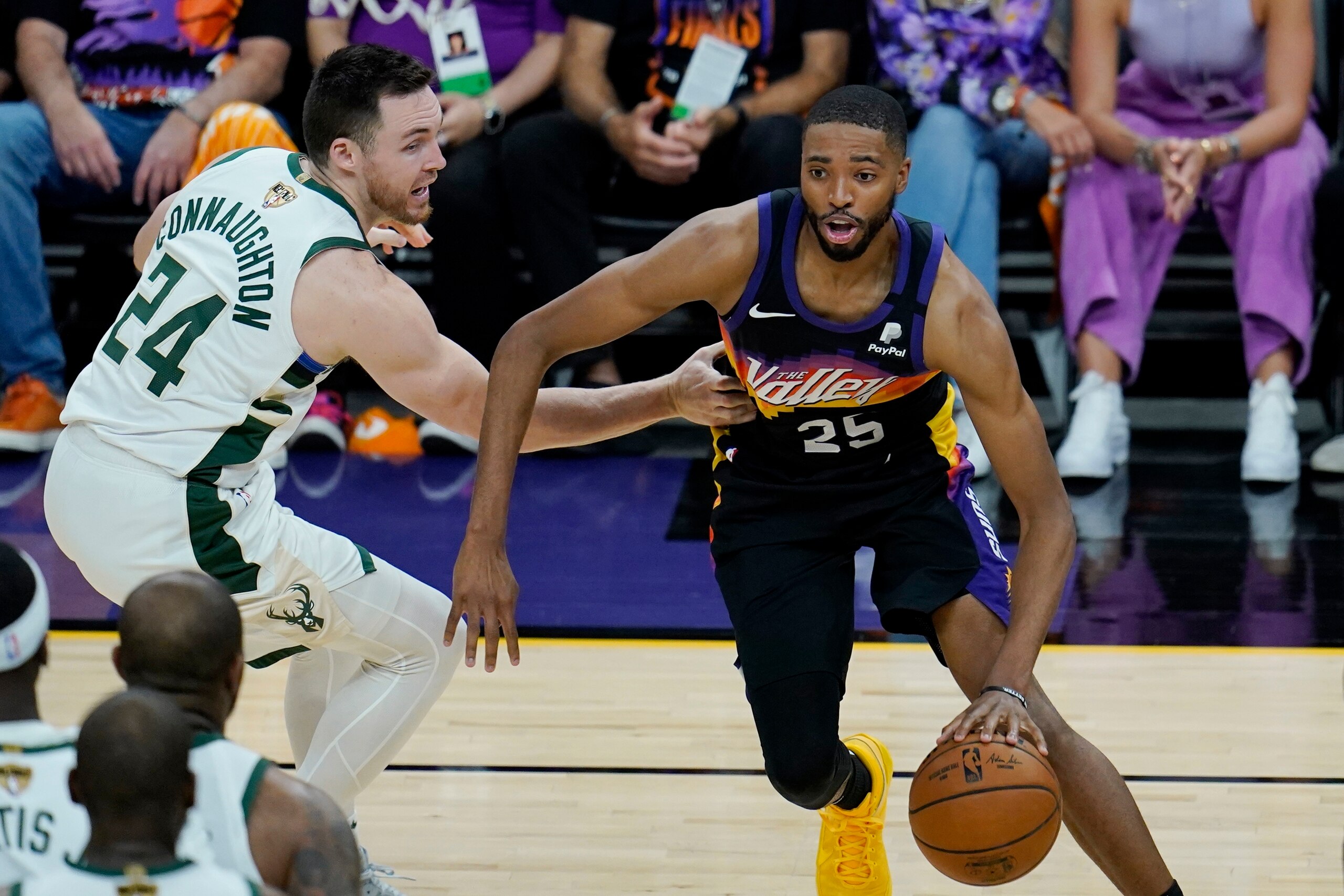 Phoenix Suns forward Mikal Bridges (25) dribbles past Milwaukee Bucks guard Pat Connaughton (24) during the second half of Game 1 of basketball's NBA Finals, Tuesday, July 6, 2021, in Phoenix. (AP Photo/Ross D. Franklin)