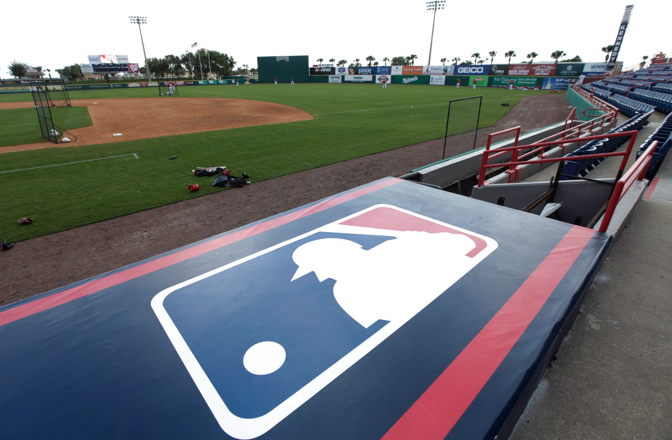 The Major League Baseball logo is seen on the dugout of Space Coast Stadium, the spring training home of the Washington Nationals, Thursday, March 1, 2012, in Viera, Fla. (AP Photo/Julio Cortez)
