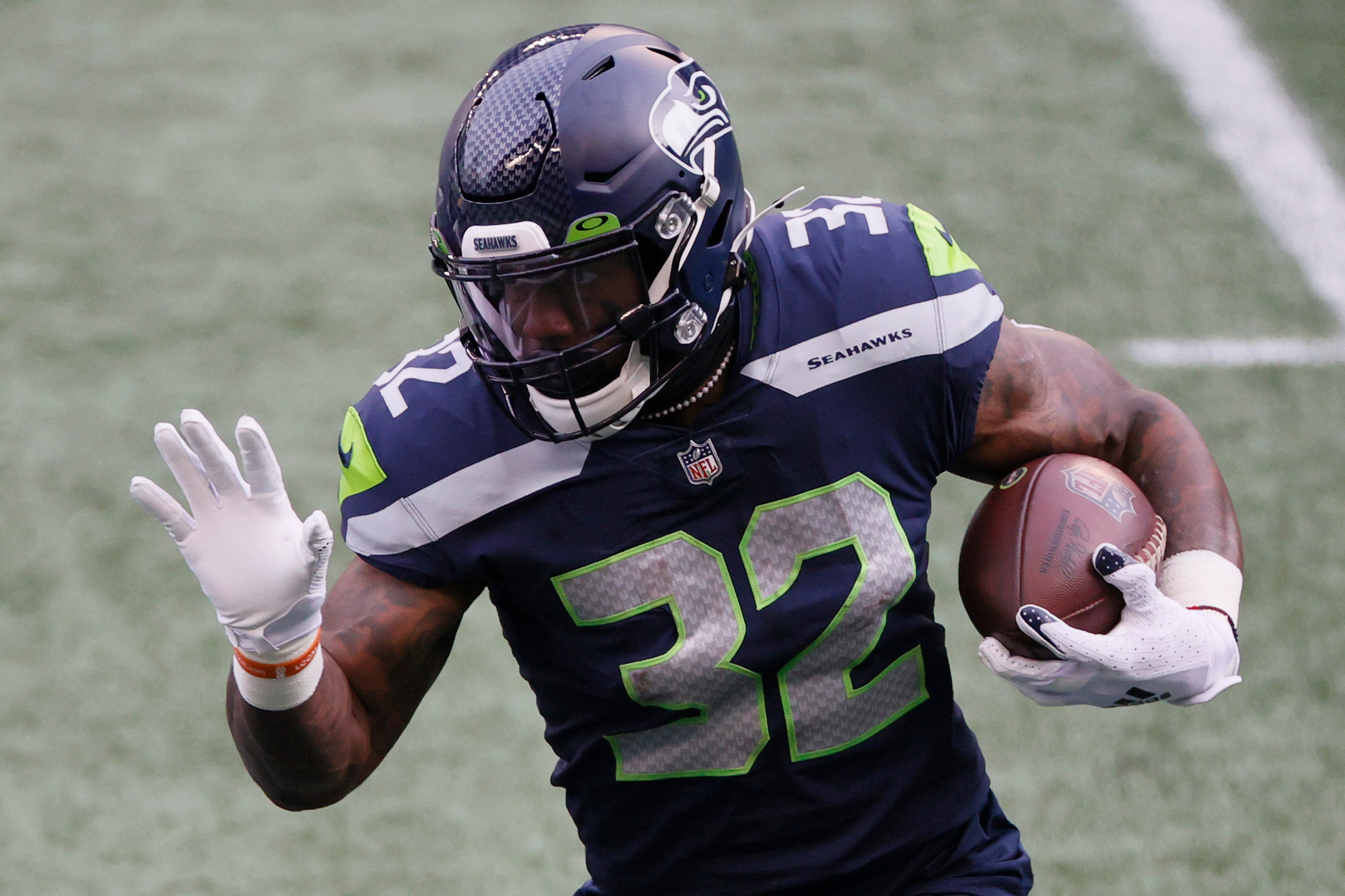 SEATTLE, WASHINGTON - JANUARY 09: Running back Chris Carson #32 of the Seattle Seahawks carries the football against the defense of the Los Angeles Rams during the first quarter of the NFC Wild Card Playoff game at Lumen Field on January 09, 2021 in Seattle, Washington. (Photo by Steph Chambers/Getty Images)