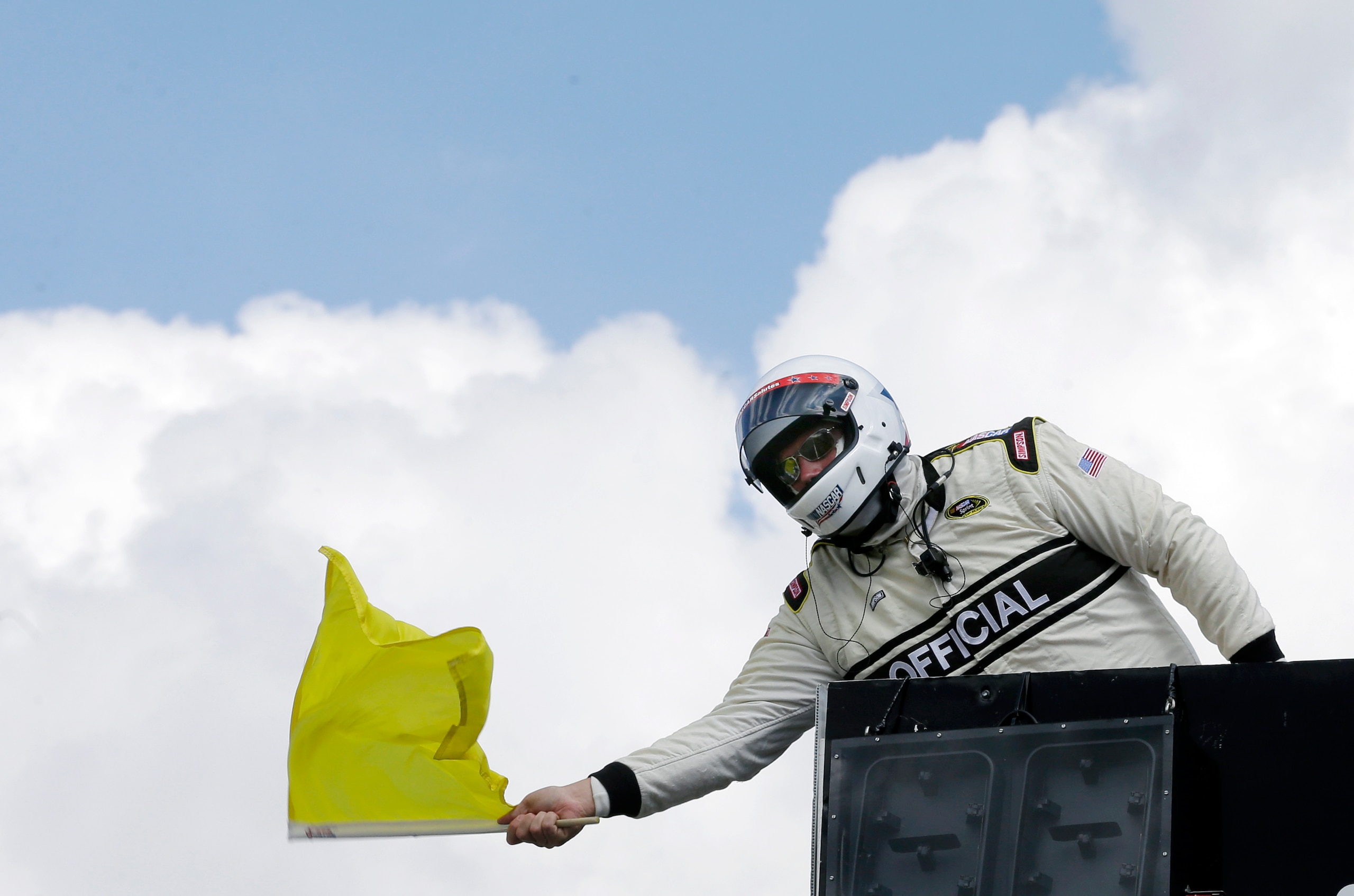 An official waves a yellow caution flag at Pocono Raceway during a NASCAR Sprint Cup Series auto race in Long Pond, Pa., Sunday, June 7, 2015. (AP Photo/Mel Evans)