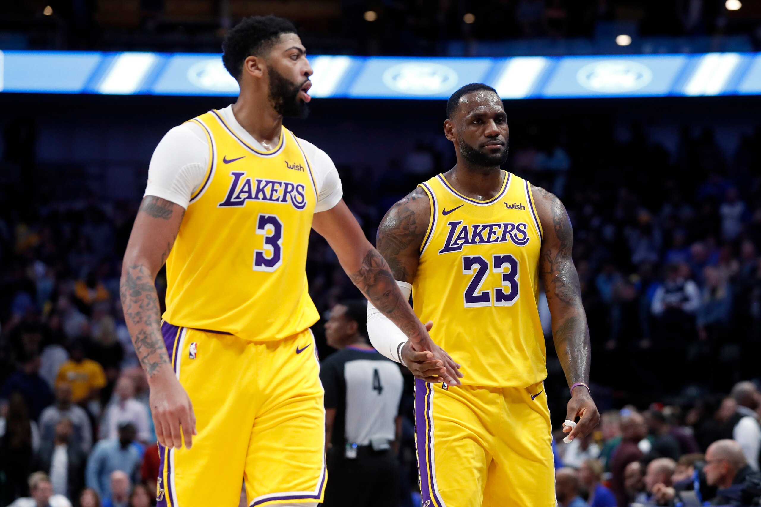 Los Angeles Lakers' Anthony Davis (3) and LeBron James (23) celebrate as they walk back to the bench in the final seconds of overtime in the team's NBA basketball game against the Dallas Mavericks in Dallas, Friday, Nov. 1, 2019. The Lakers won 119-110. (AP Photo/Tony Gutierrez)