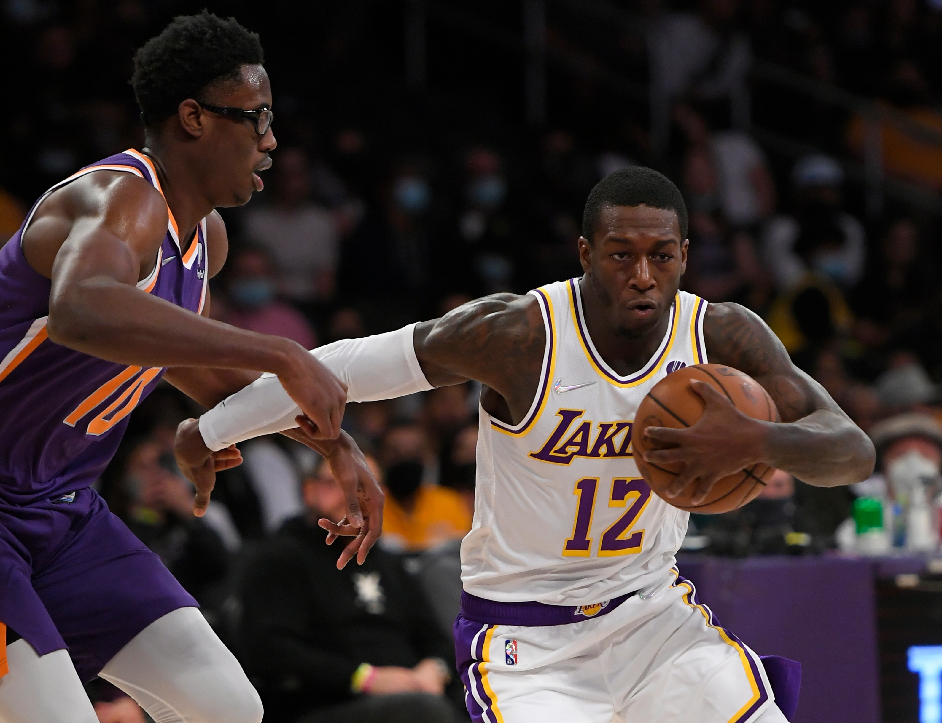 Los Angeles Lakers guard Kendrick Nunn (12) dribbles past Phoenix Suns forward Jalen Smith (10) in the second half of a preseason NBA basketball game in Los Angeles, Sunday, Oct. 10, 2021. (AP Photo/John McCoy)