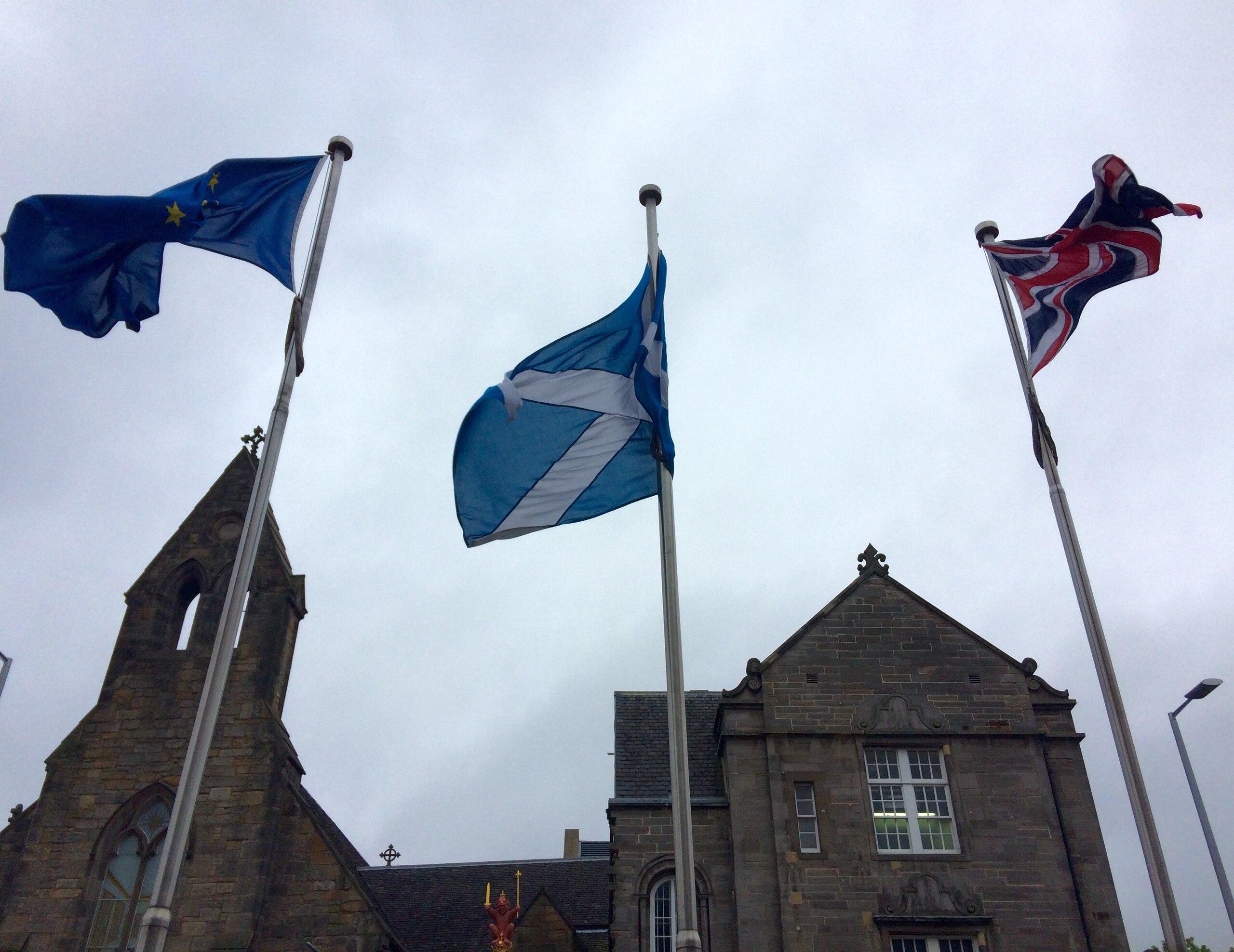 In this picture taken on Thursday, May 26, 2016, an EU flag, a Scottish flag and an Union Jack, left to right, wave outside Scottish parliament in front “The Queen’s Gallery” in Edinburgh. Scottish voters who want Britain to remain part of the EU would be so unhappy if it decided to break away that they would back a second referendum on forming their own independent nation. (AP Photo/ Dorothee Thiesing)