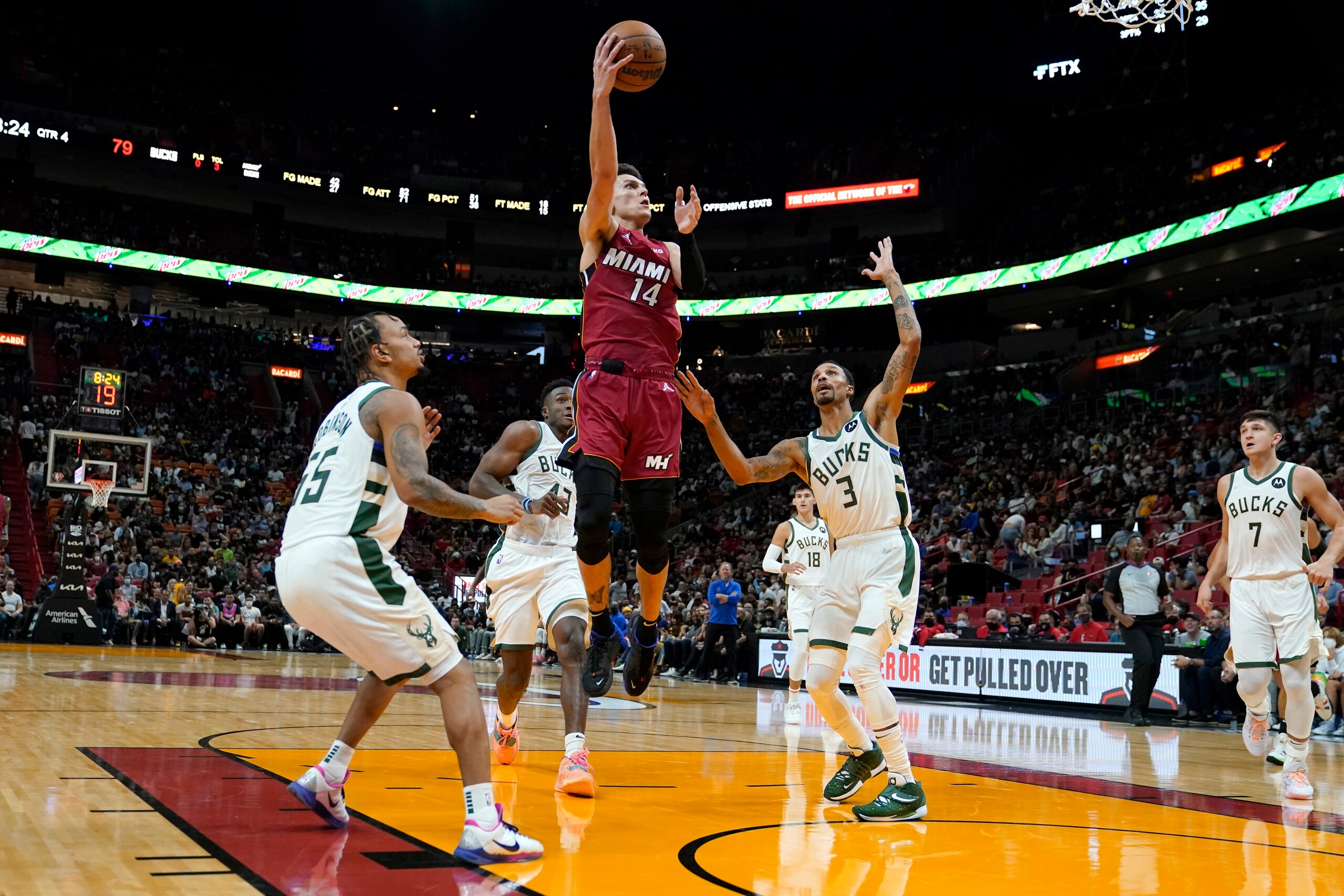 Miami Heat guard Tyler Herro (14) shoots above Milwaukee Bucks guard Justin Robinson (55), forward Thanasis Antetokounmpo (43) and guard George Hill (3) during the second half of an NBA basketball game Thursday, Oct. 21, 2021, in Miami. The Heat won 137-95. (AP Photo/Lynne Sladky)