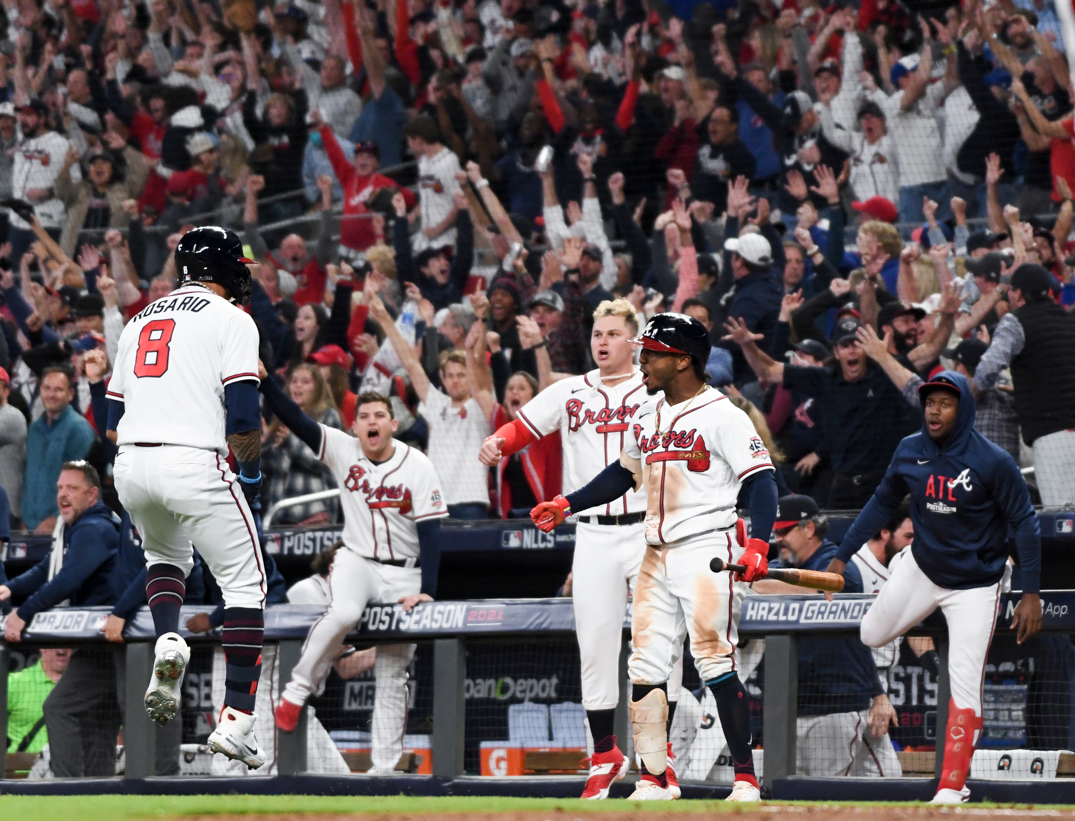 Atlanta, GA - October 23: Atlanta Braves' Eddie Rosario, from left, celebrates while approaching home off a three-run home run as Joc Pederson and Ozzie Albies wait during the fourth inning in game six in the 2021 National League Championship Series against the Los Angeles Dodgers at Truist Park on Saturday, Oct. 23, 2021 in Atlanta, GA. (Wally Skalij / Los Angeles Times via Getty Images)