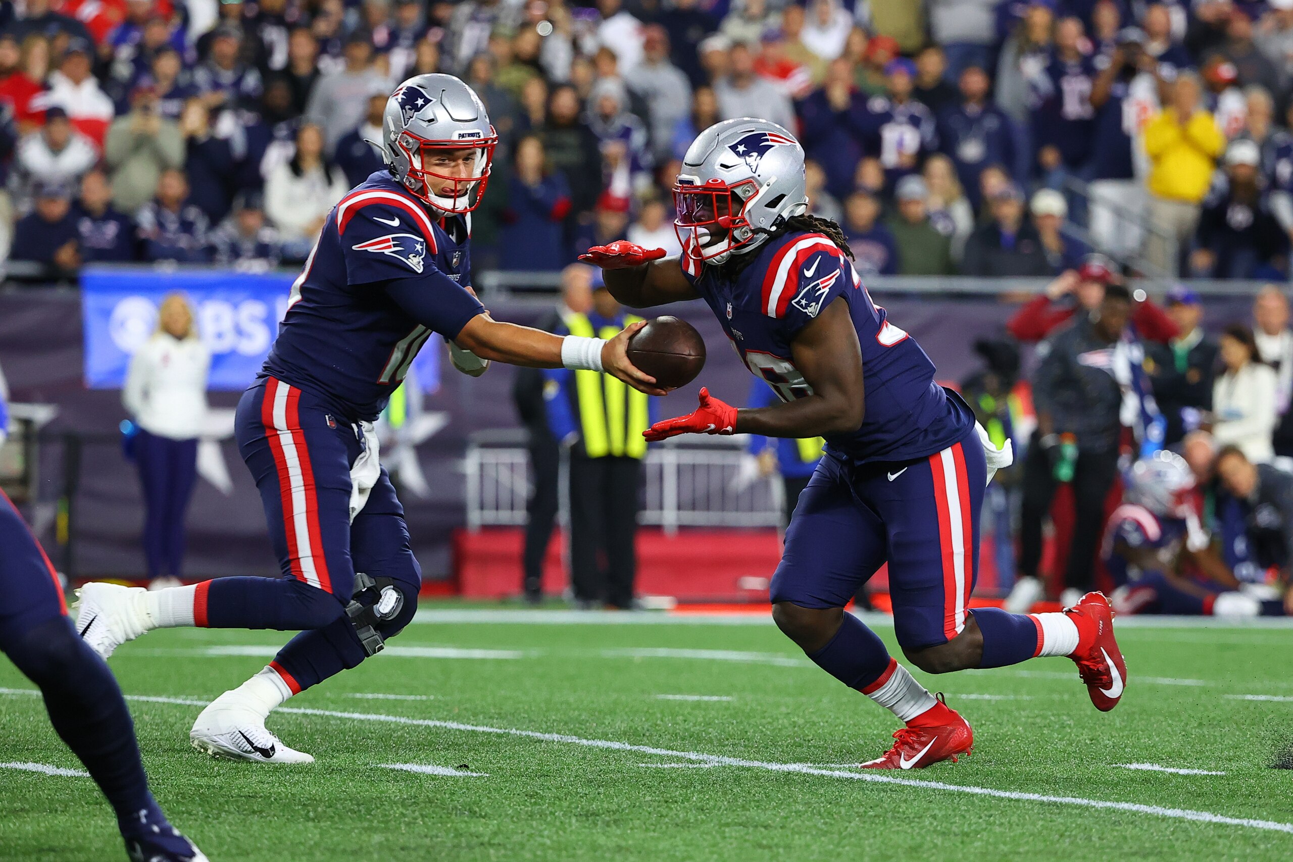 FOXBOROUGH, MA - OCTOBER 17:  New England Patriots quarterback Mac Jones (10) hands off to New England Patriots running back Rhamondre Stevenson (38) during the National Football League game between the New England Patriots and the Dallas Cowboys on October 17, 2021 at Gillette Stadium in Foxborough, MA.    (Photo by Rich Graessle/Icon Sportswire via Getty Images)