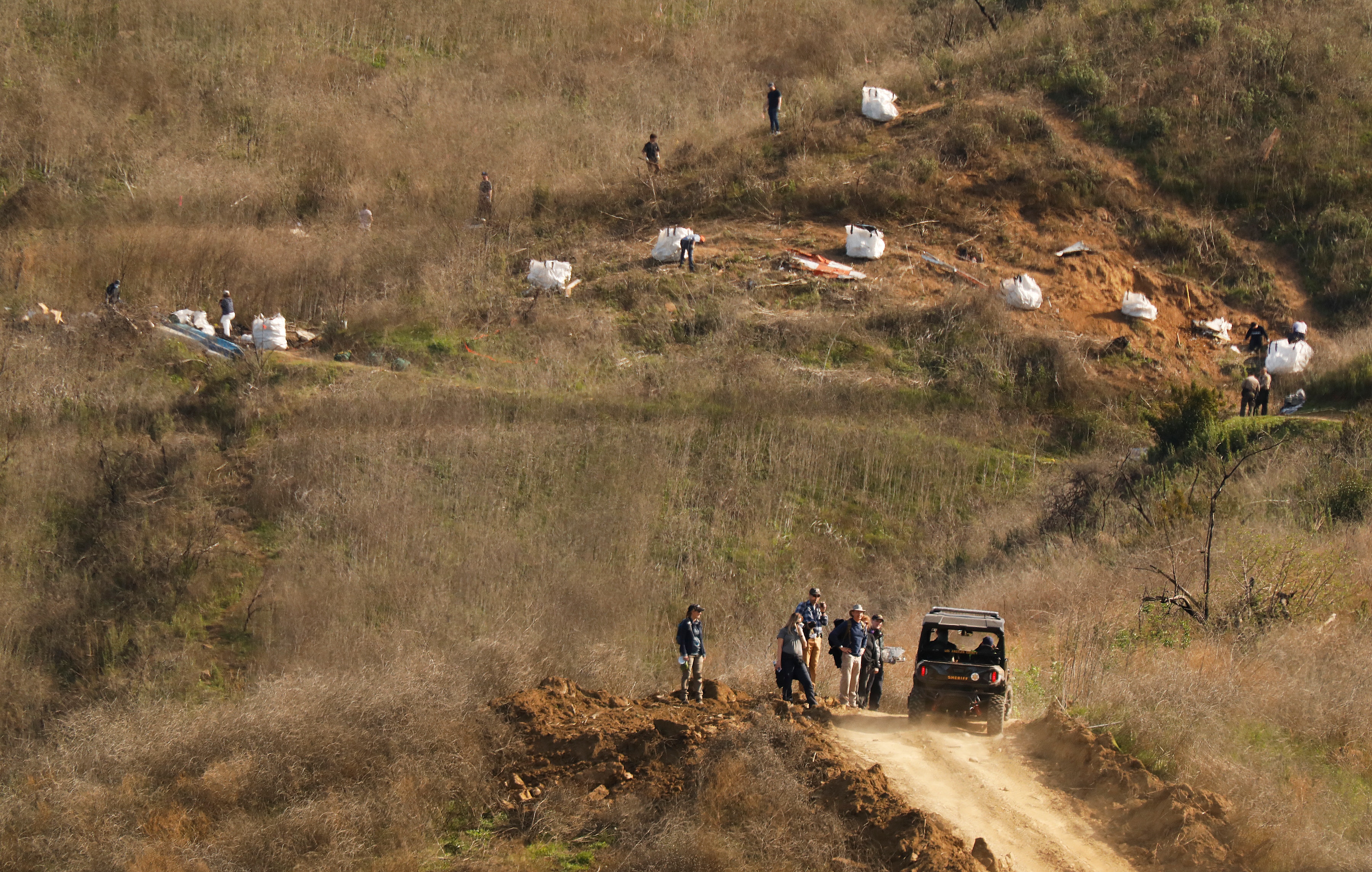 CALABASAS, CA - JANUARY 28, 2020:   Investigators walk down the bulldozed dirt road Tuesday morning after working at the hillside scene of the helicopter crash that killed Kobe Bryant and eight other people Sunday morning near the intersection of Las Virgenes Road and Willow Glen Street January 28, 2020 in Calabasas, California. (Photo by Al Seib/Los Angeles Times via Getty Images)