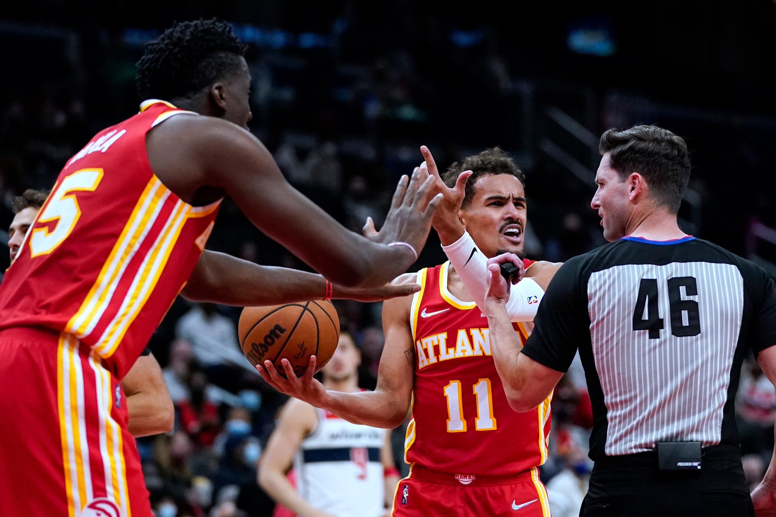 Atlanta Hawks center Clint Capela (15) and guard Trae Young (11) plead their case with referee Ben Taylor (46) during the first half of the team's NBA basketball game against the Washington Wizards, Thursday, Oct. 28, 2021, in Washington. (AP Photo/Alex Brandon)