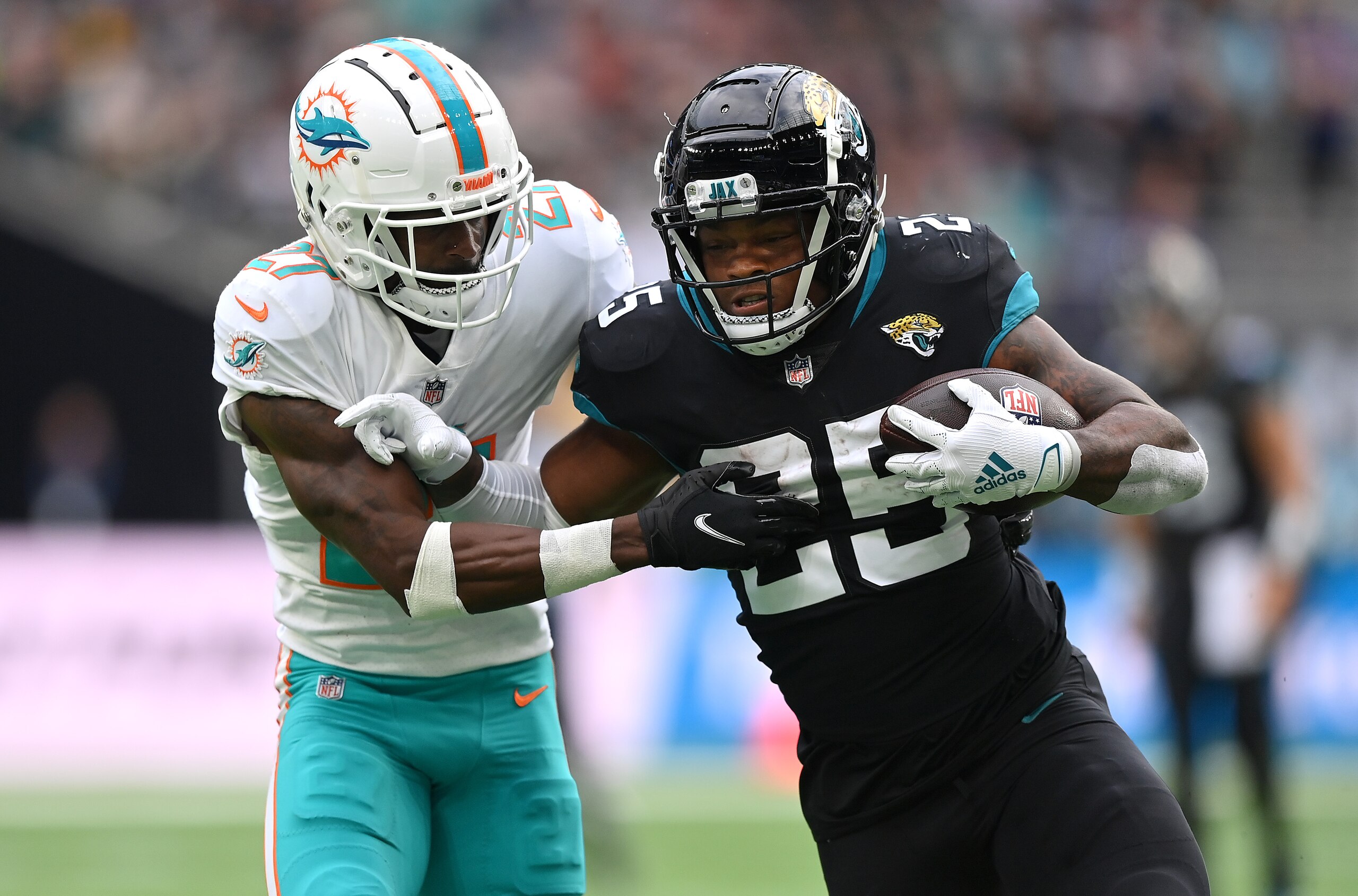 LONDON, ENGLAND - OCTOBER 17: James Robinson #25 of the Jacksonville Jaguars is tackled by Justin Coleman #27 of the Miami Dolphins during the NFL London 2021 match between Miami Dolphins and Jacksonville Jaguars at Tottenham Hotspur Stadium on October 17, 2021 in London, England. (Photo by Justin Setterfield/Getty Images)