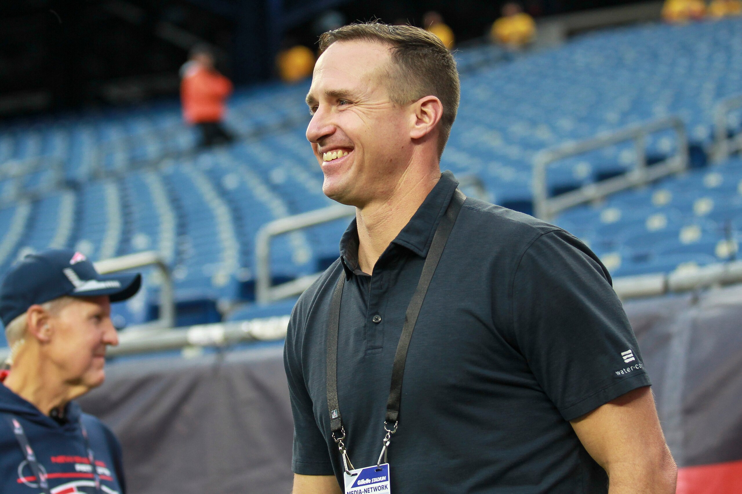 NBC Sports Football Night in America commentator Drew Brees walks onto the field prior to an NFL football game between the New England Patriots and the Tampa Bay Buccaneers, Sunday, Oct. 3, 2021, in Foxborough, Mass. (AP Photo/Stew Milne)