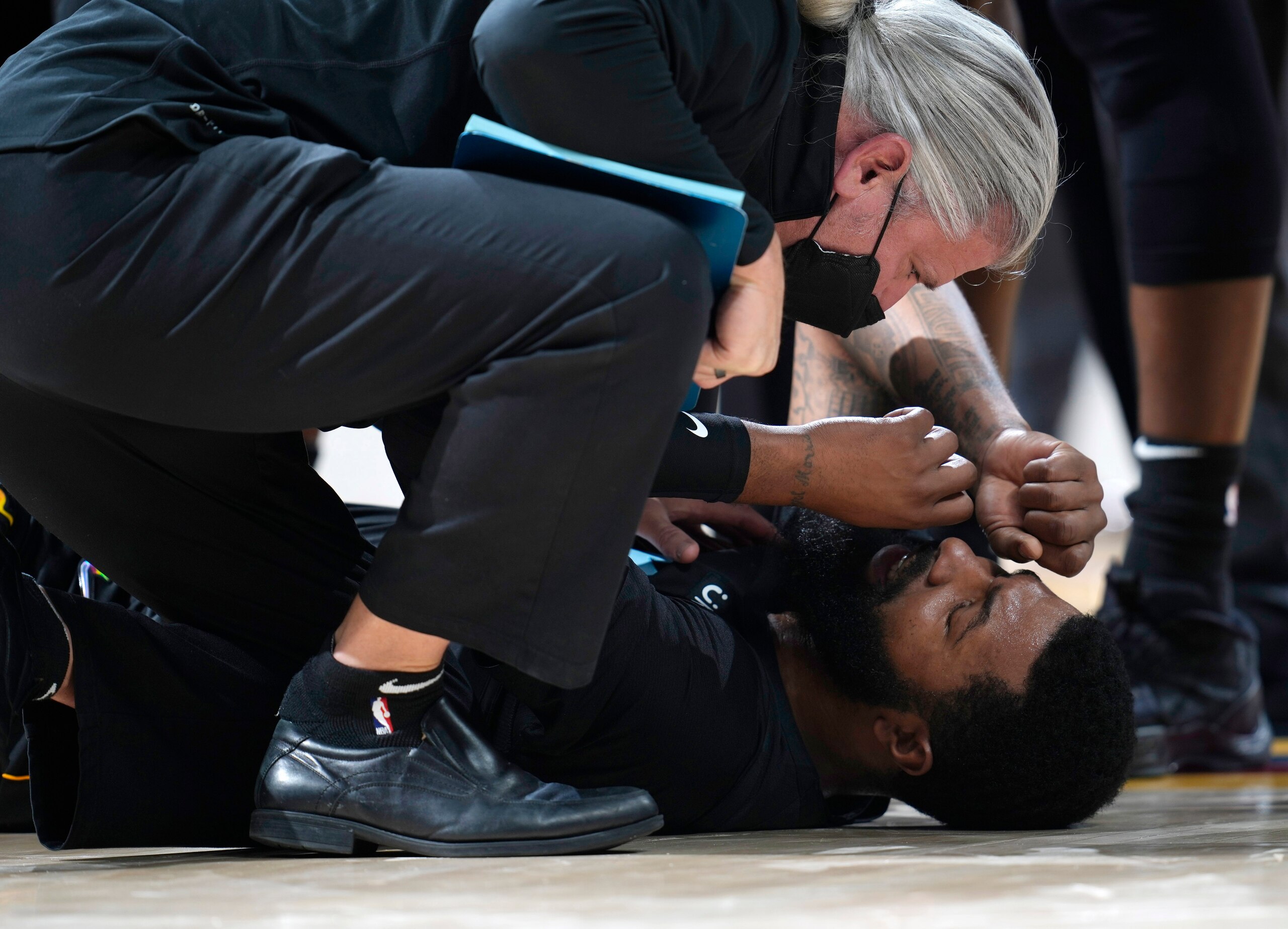 Miami Heat forward Markieff Morris, bottom, is attended to after being in an altercation with Denver Nuggets center Nikola Jokic in the second half of an NBA basketball game Monday, Nov. 8, 2021, in Denver. Morris walked off the court after being examined and Jokic was ejected. (AP Photo/David Zalubowski)