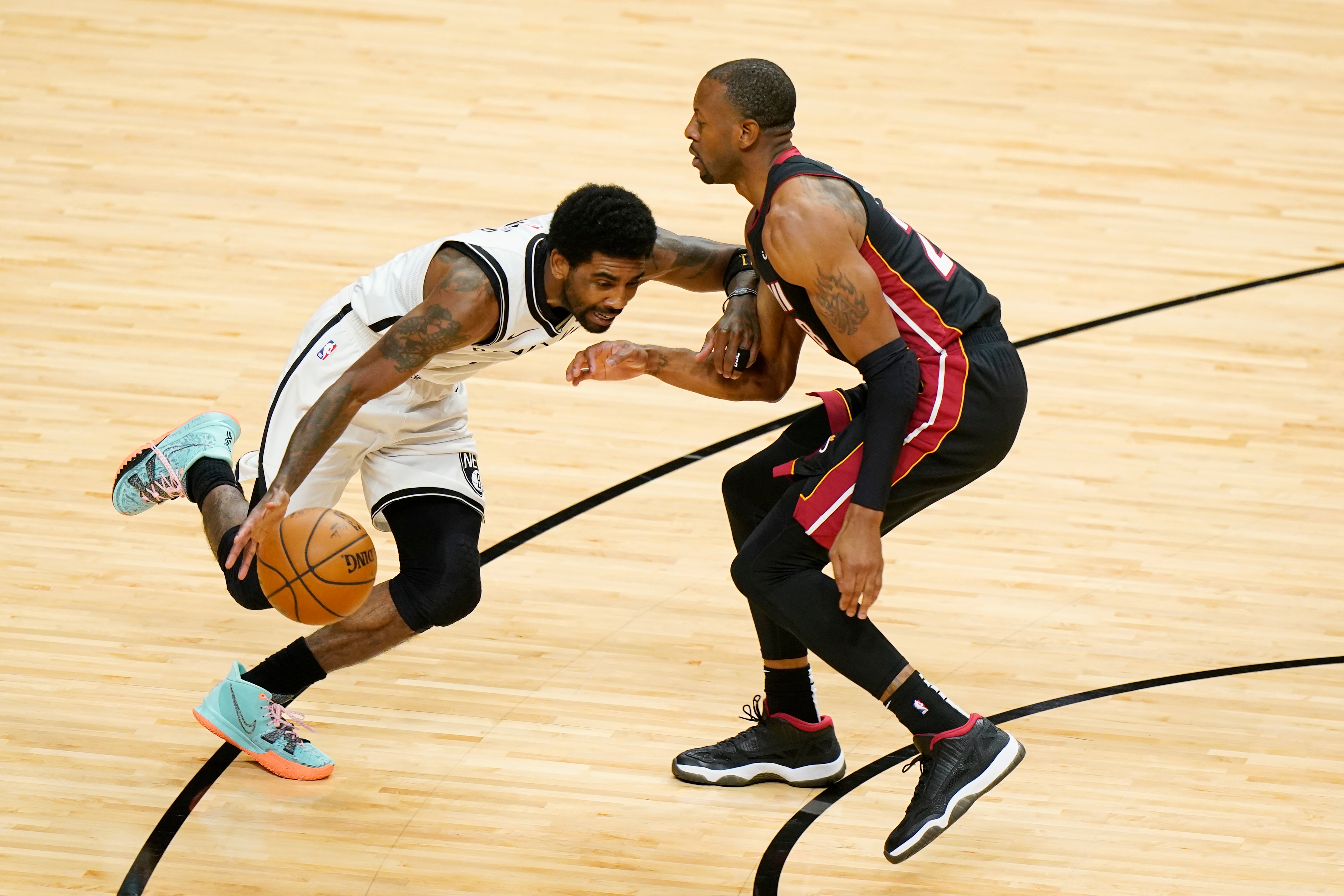 Brooklyn Nets guard Kyrie Irving, left, drives up against Miami Heat forward Andre Iguodala during the first half of an NBA basketball game, Sunday, April 18, 2021, in Miami. (AP Photo/Wilfredo Lee)
