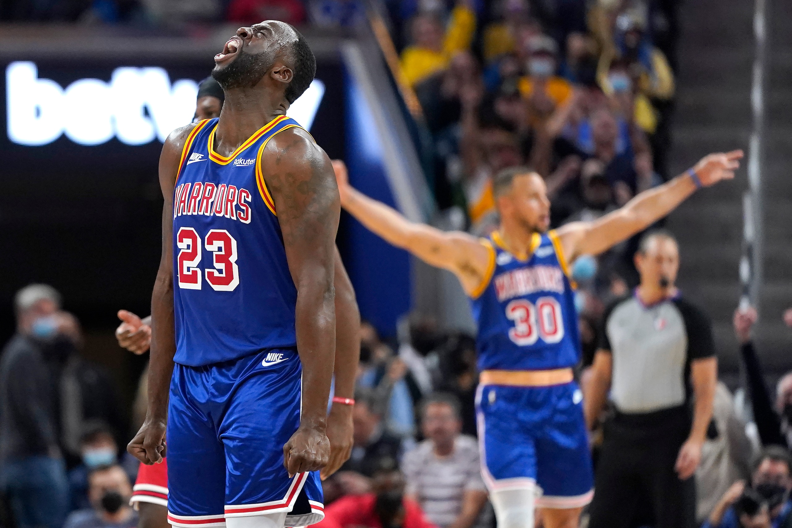 Golden State Warriors forward Draymond Green (23) and guard Stephen Curry (30) react after Green's 3-point basket against the Chicago Bulls during the first half of an NBA basketball game in San Francisco, Friday, Nov. 12, 2021. (AP Photo/Jeff Chiu)