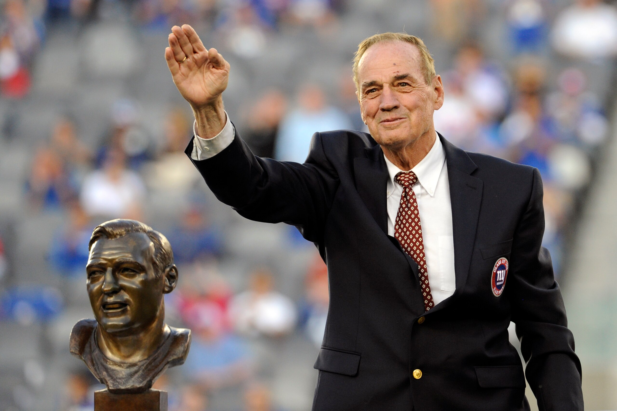 Former New York Giants linebacker Sam Huff waves to the fans as he stands behind his Hall of Fame bust during the halftime show of an NFL football game between the New York Giants and the Denver Broncos Sunday, Sept. 15, 2013, in East Rutherford, N.J. (AP Photo/Bill Kostroun)