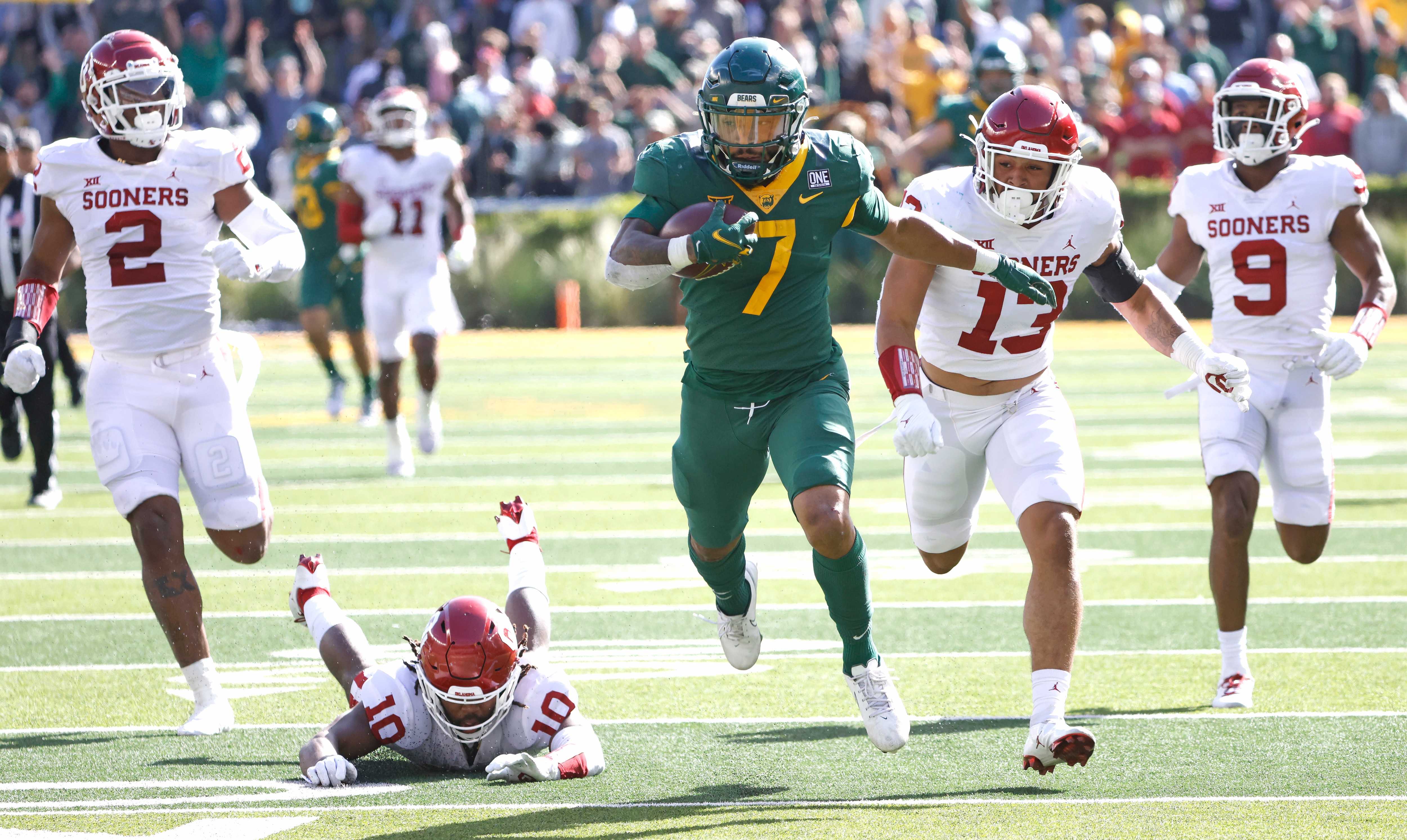 WACO, TX - NOVEMBER 13: Abram Smith #7 of the Baylor Bears carries the ball for a big gain against a host of Oklahoma Sooners defenders in the second half at McLane Stadium on November 13, 2021 in Waco, Texas. Baylor won 27-14. (Photo by Ron Jenkins/Getty Images)