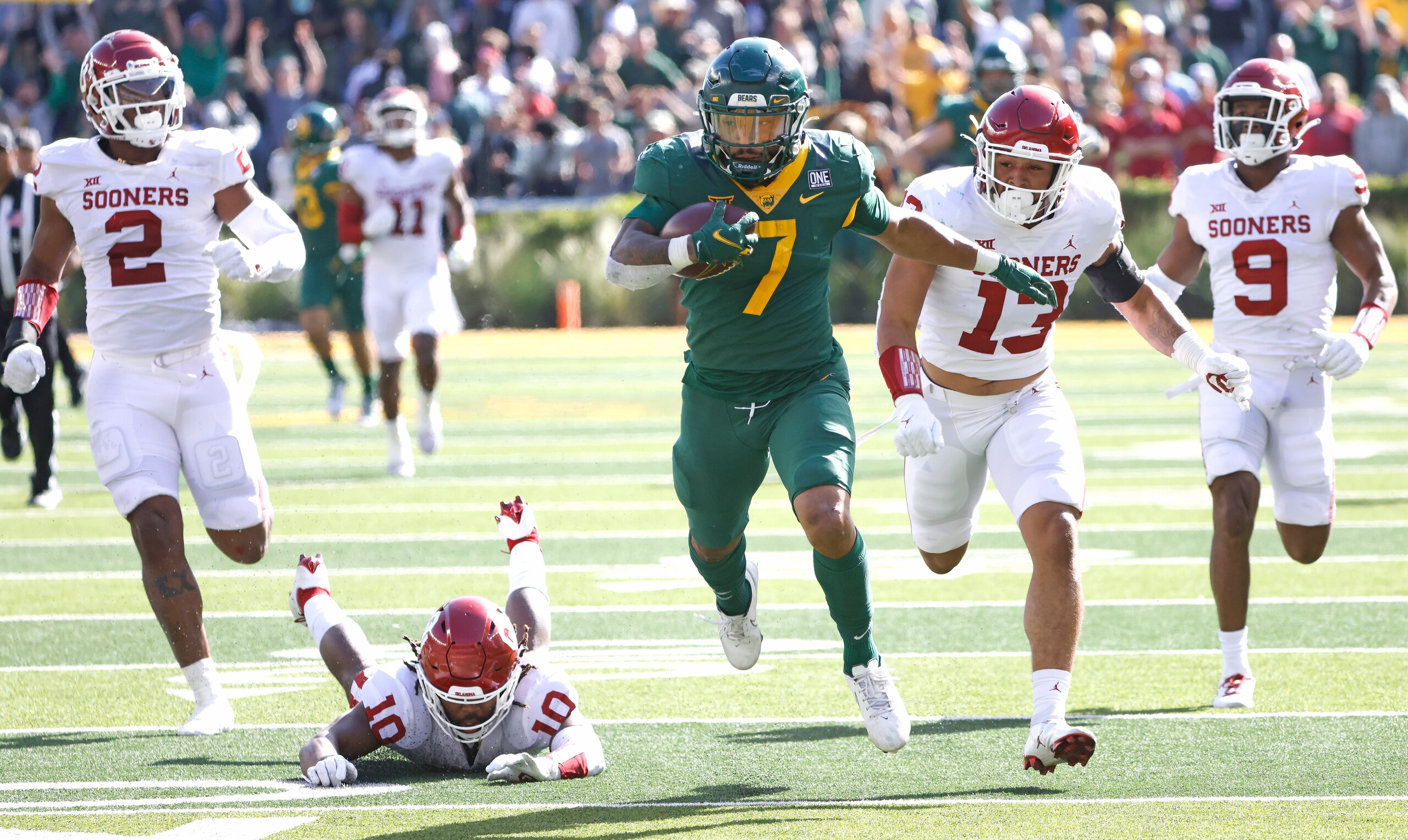 WACO, TX - NOVEMBER 13: Abram Smith #7 of the Baylor Bears carries the ball for a big gain against a host of Oklahoma Sooners defenders in the second half at McLane Stadium on November 13, 2021 in Waco, Texas. Baylor won 27-14. (Photo by Ron Jenkins/Getty Images)