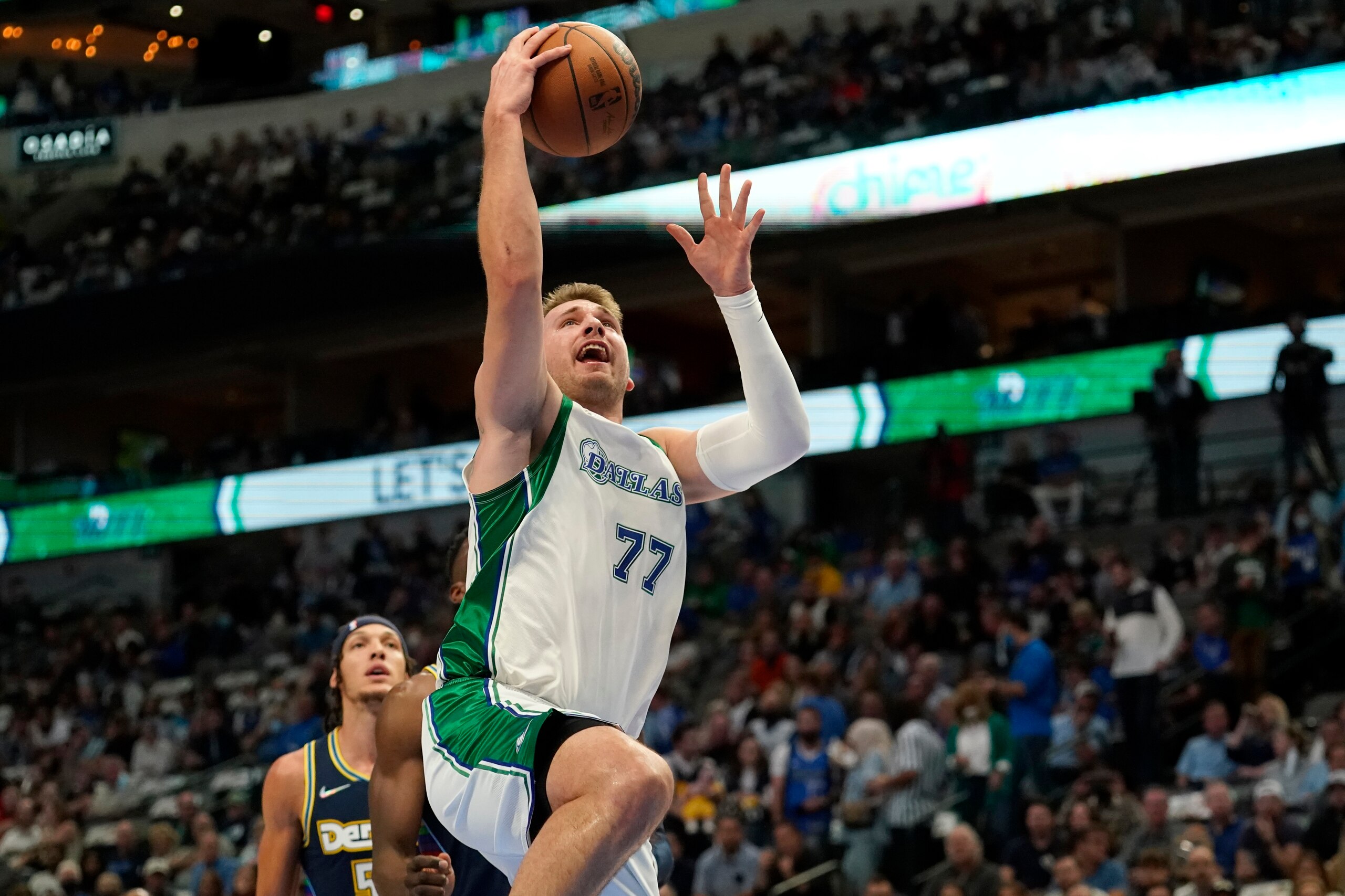 Dallas Mavericks guard Luka Doncic (77) leaps to the basket for a shot after getting past Denver Nuggets defenders in the first half of an NBA basketball game in Dallas, Monday, Nov. 15, 2021. (AP Photo/Tony Gutierrez)