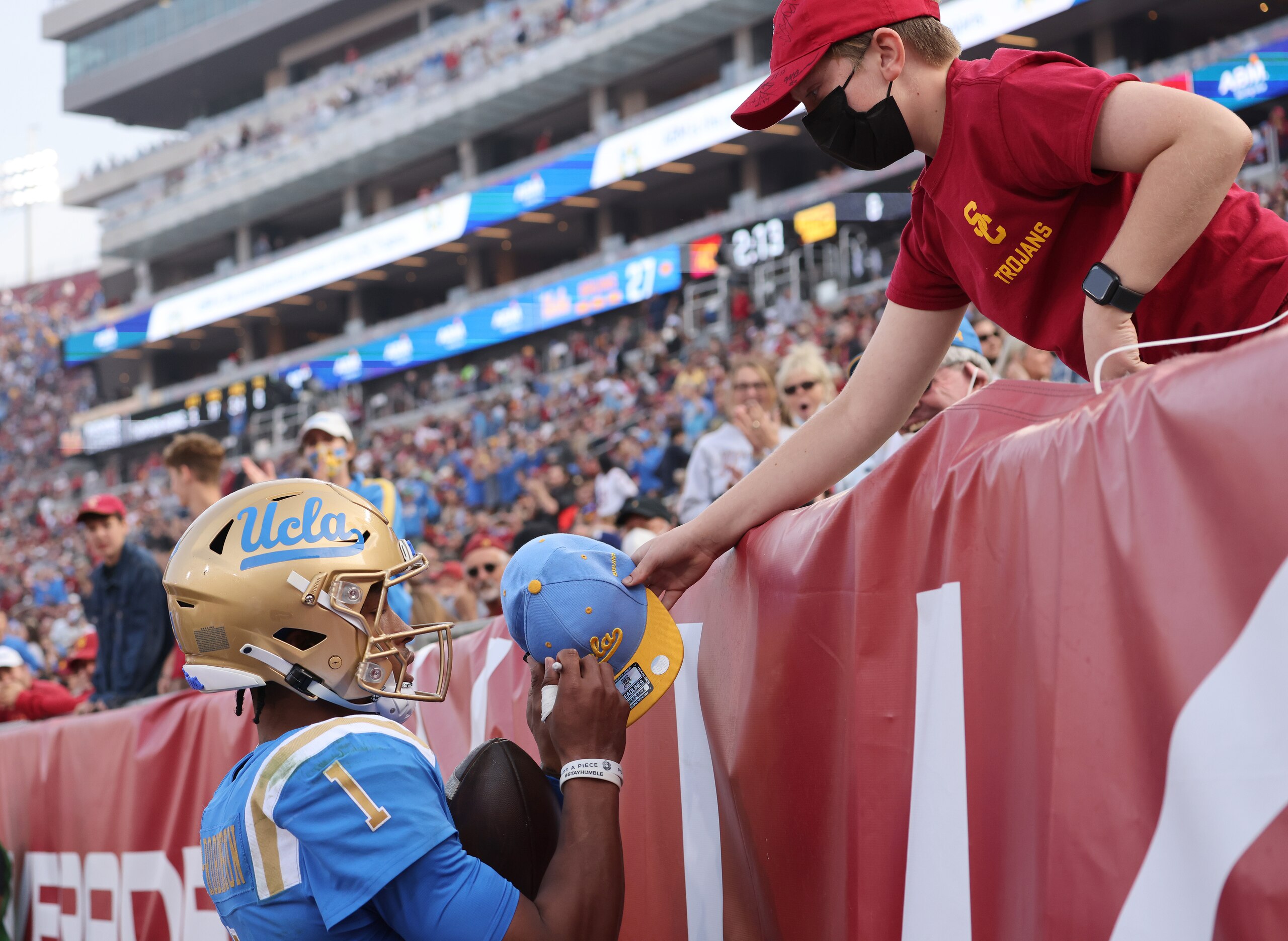 LOS ANGELES, CALIFORNIA - NOVEMBER 20: Dorian Thompson-Robinson #1 of the UCLA Bruins celebrates his touchdown run, to take a 28-10 lead over the USC Trojans, by signing an autograph, resulting in a penalty, during the second quarter at Los Angeles Memorial Coliseum on November 20, 2021 in Los Angeles, California. (Photo by Harry How/Getty Images) LOS ANGELES, CALIFORNIA - NOVEMBER 20: Dorian Thompson-Robinson #1 of the UCLA Bruins celebrates his touchdown run, to take a 28-10 lead over the USC Trojans, by signing an autograph, resulting in a penalty, during the second quarter at Los Angeles Memorial Coliseum on November 20, 2021 in Los Angeles, California. (Photo by Harry How/Getty Images)